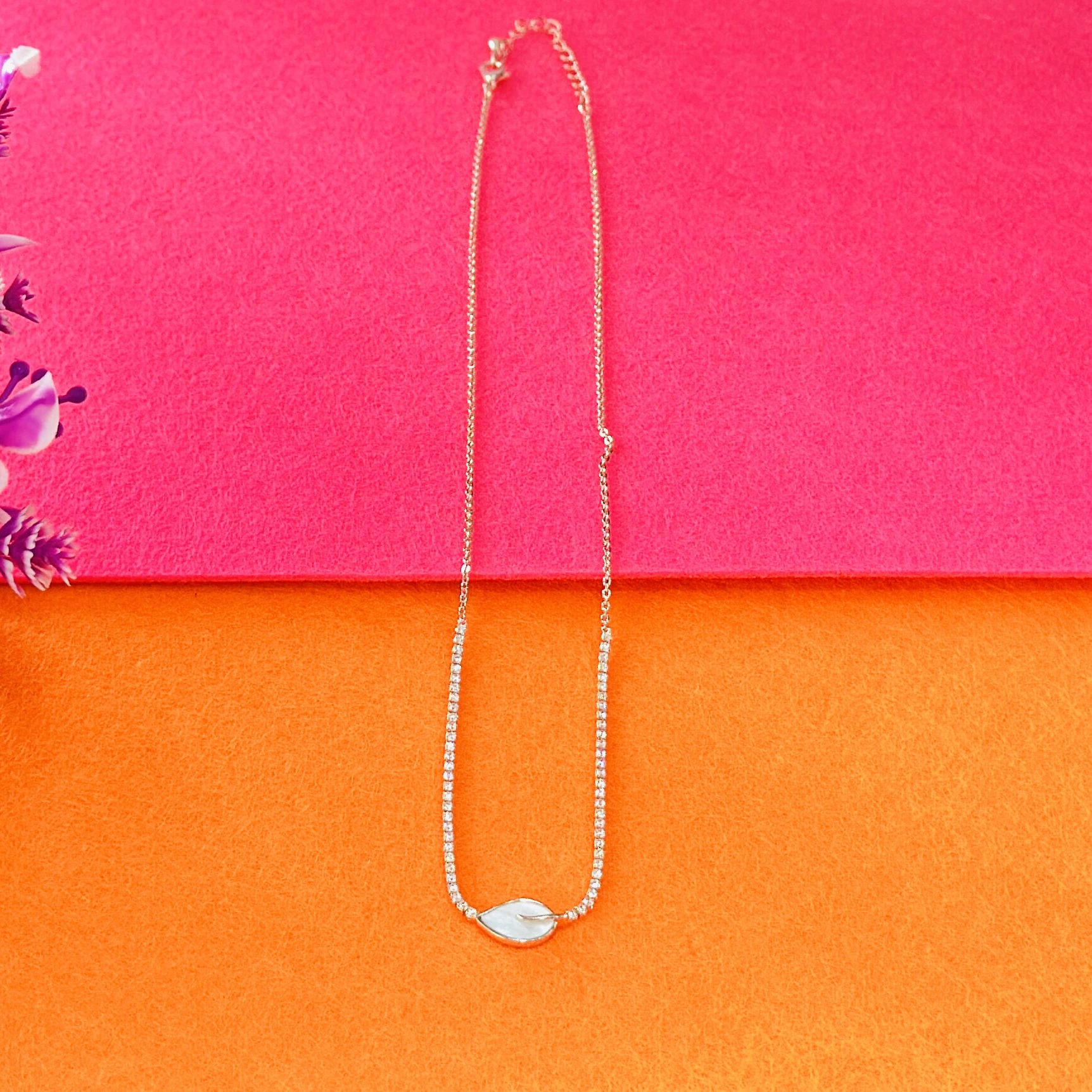 Gold plated chain necklace with a leaf-shaped white pendant.
