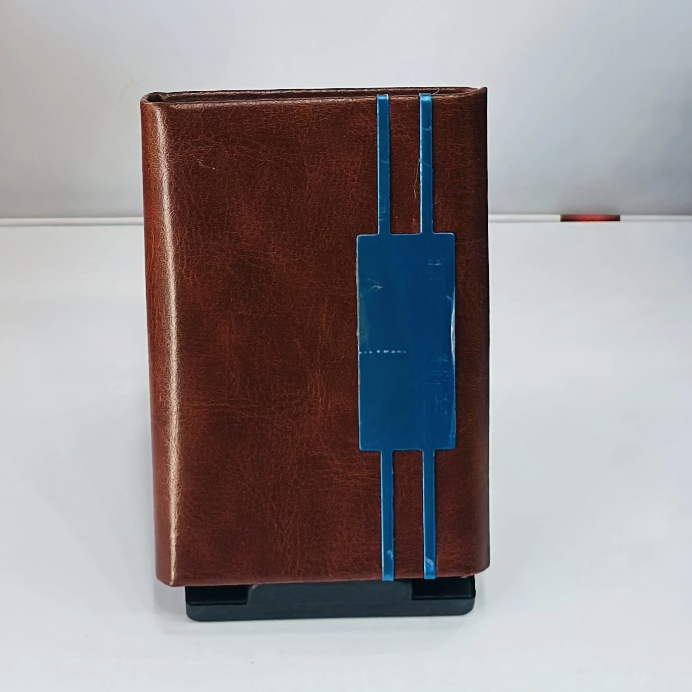brown leather business card holder with blue metal accents.