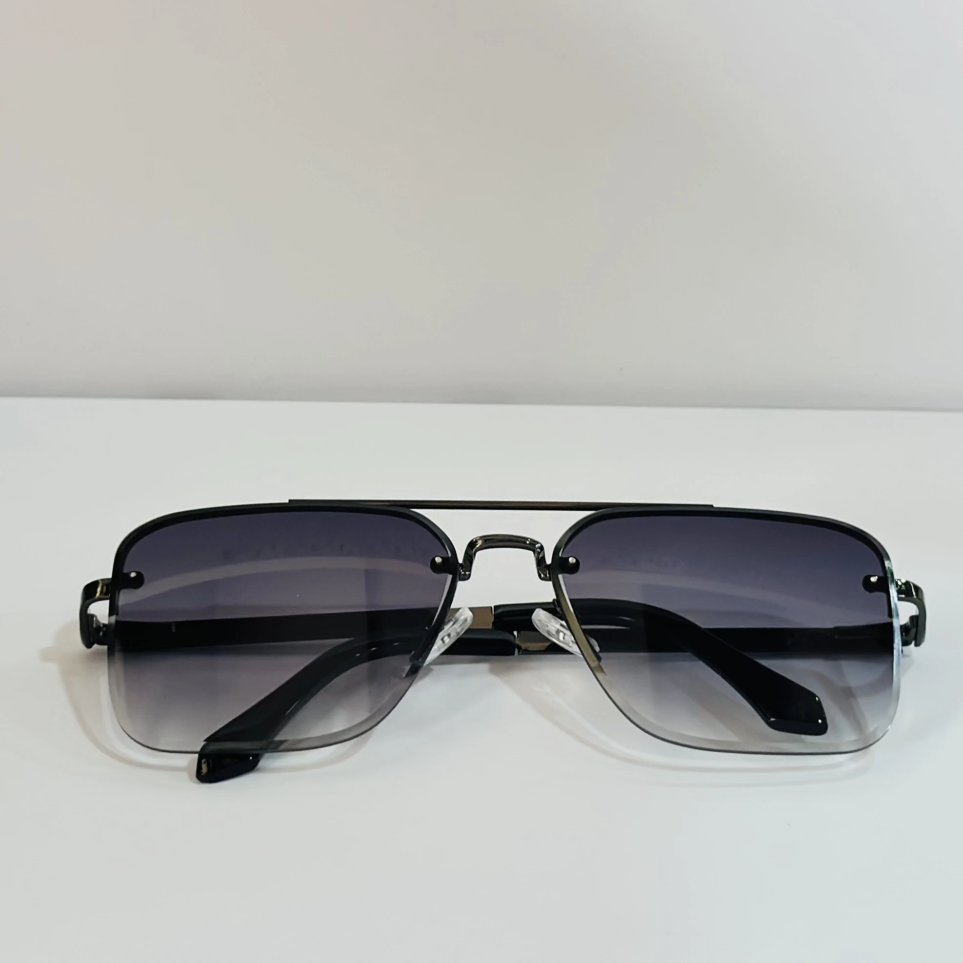 pair of aviator-style sunglasses with a black metal frame and grey gradient lenses.