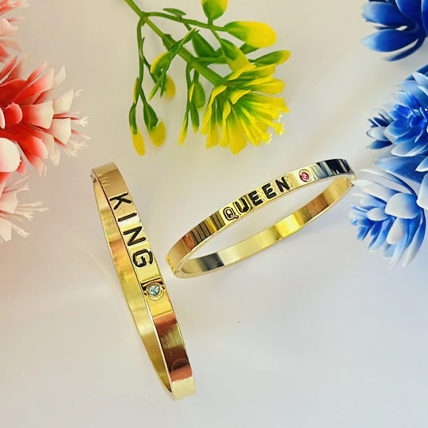 Gold plated "Queen" cuff bracelet with a pink stone accent.