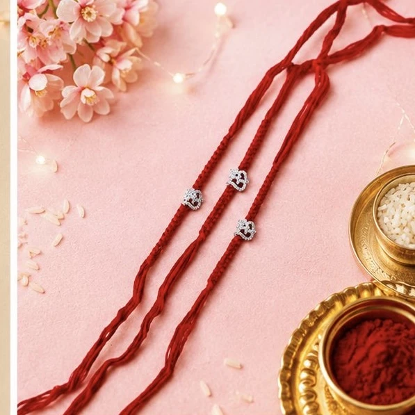 Rakhi featuring red threads and small, silver-toned Om charms.