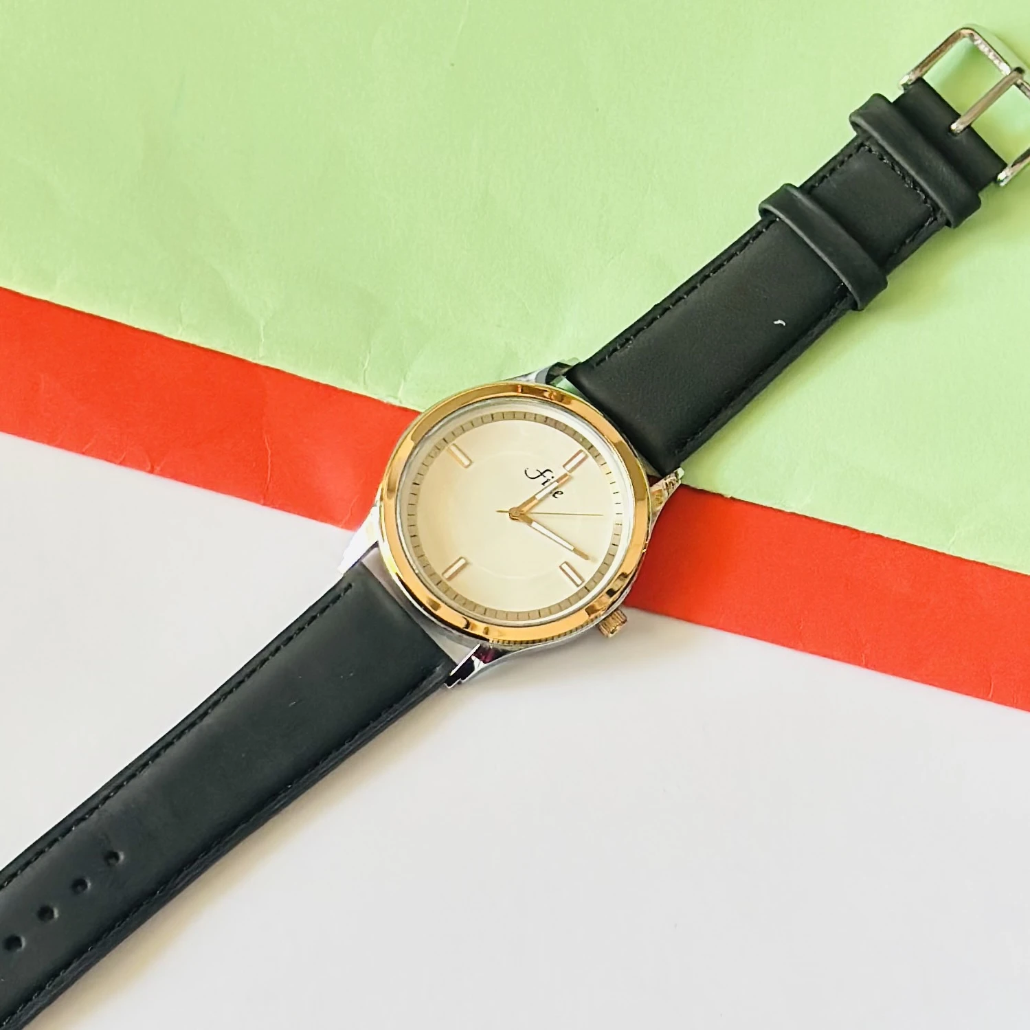Analog wristwatch with a gold-tone case and a black leather strap.