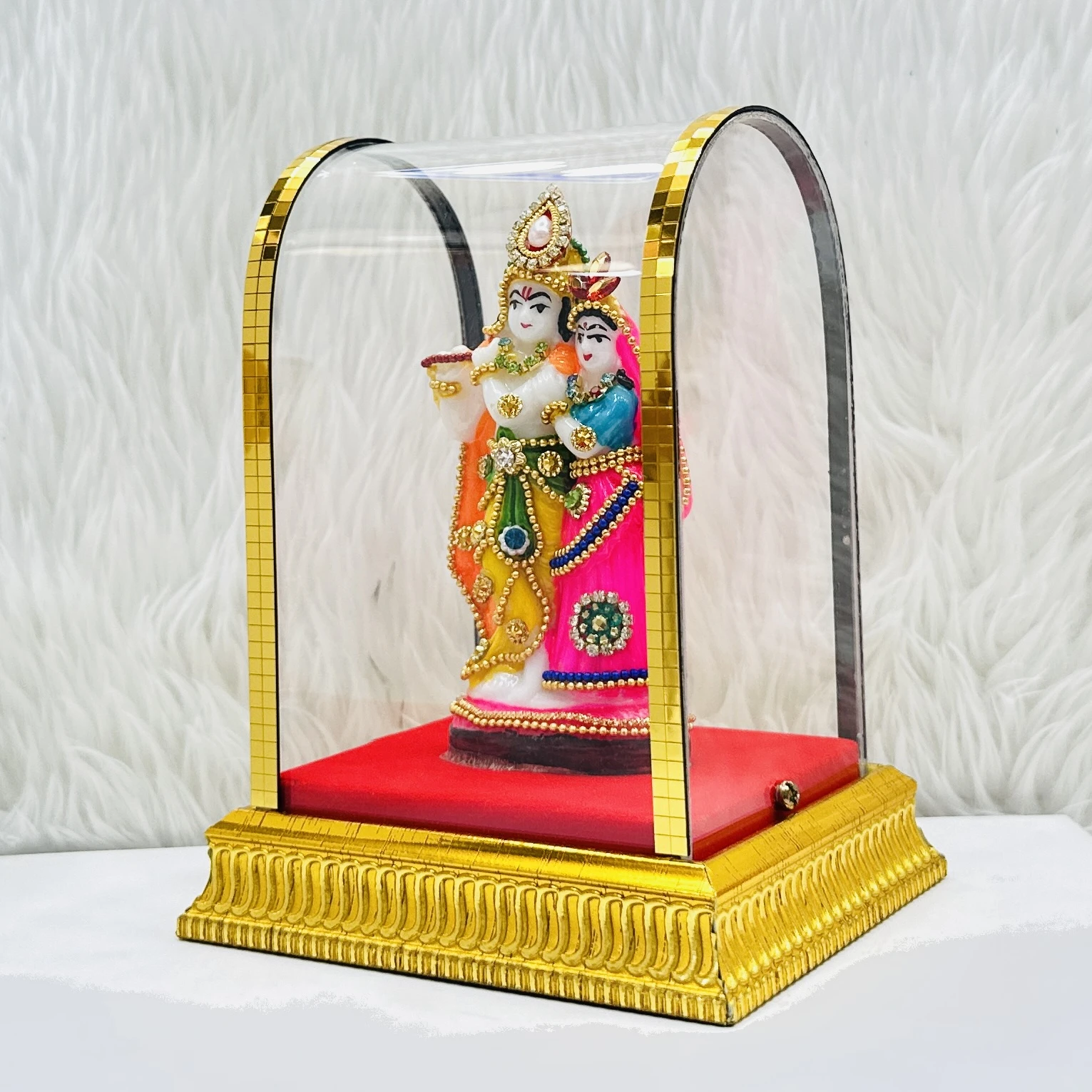 Radha Krishna statue enclosed in a protective glass case.