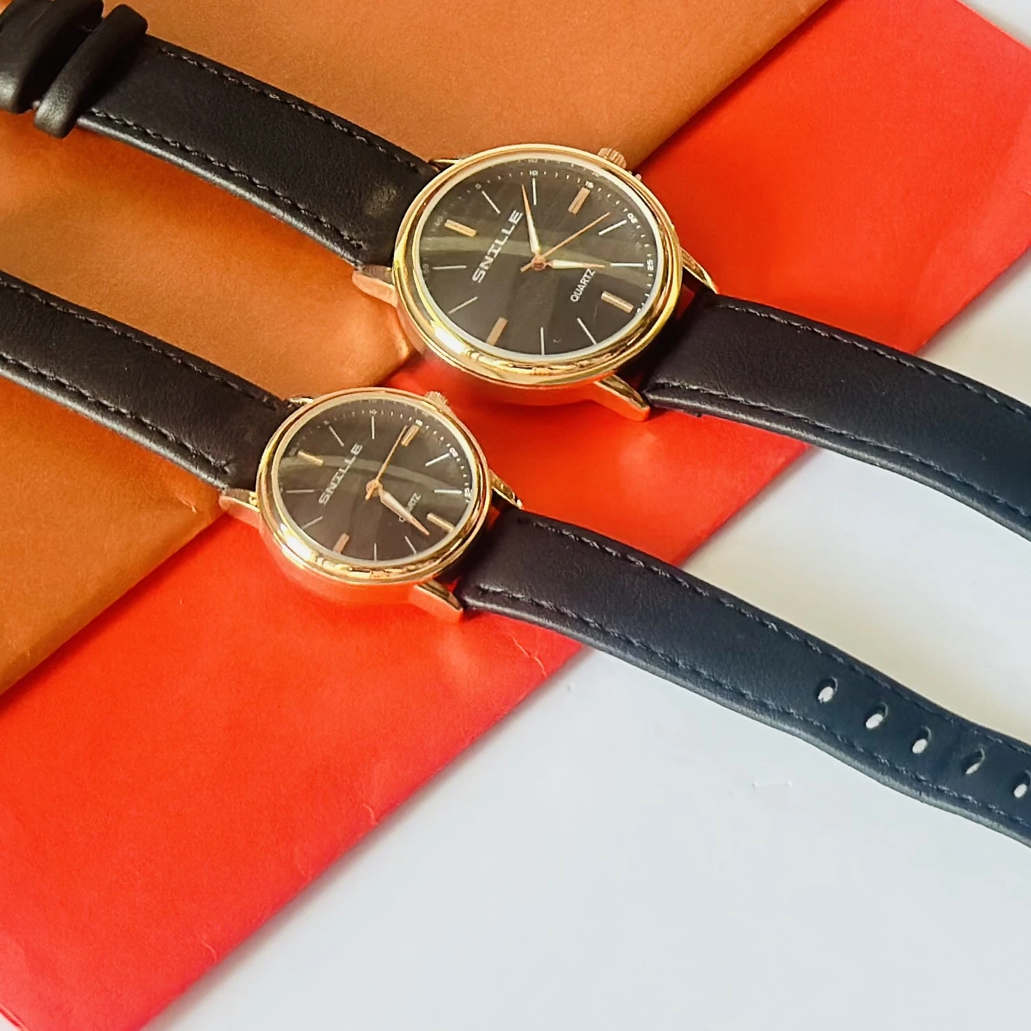 black "Snille" quartz watches with gold-tone cases and black faux leather straps