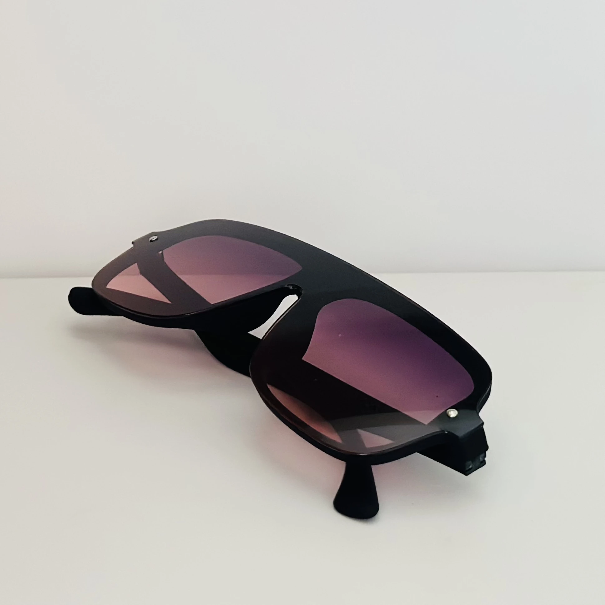 Black frame aviator-style sunglasses with pink gradient lenses.