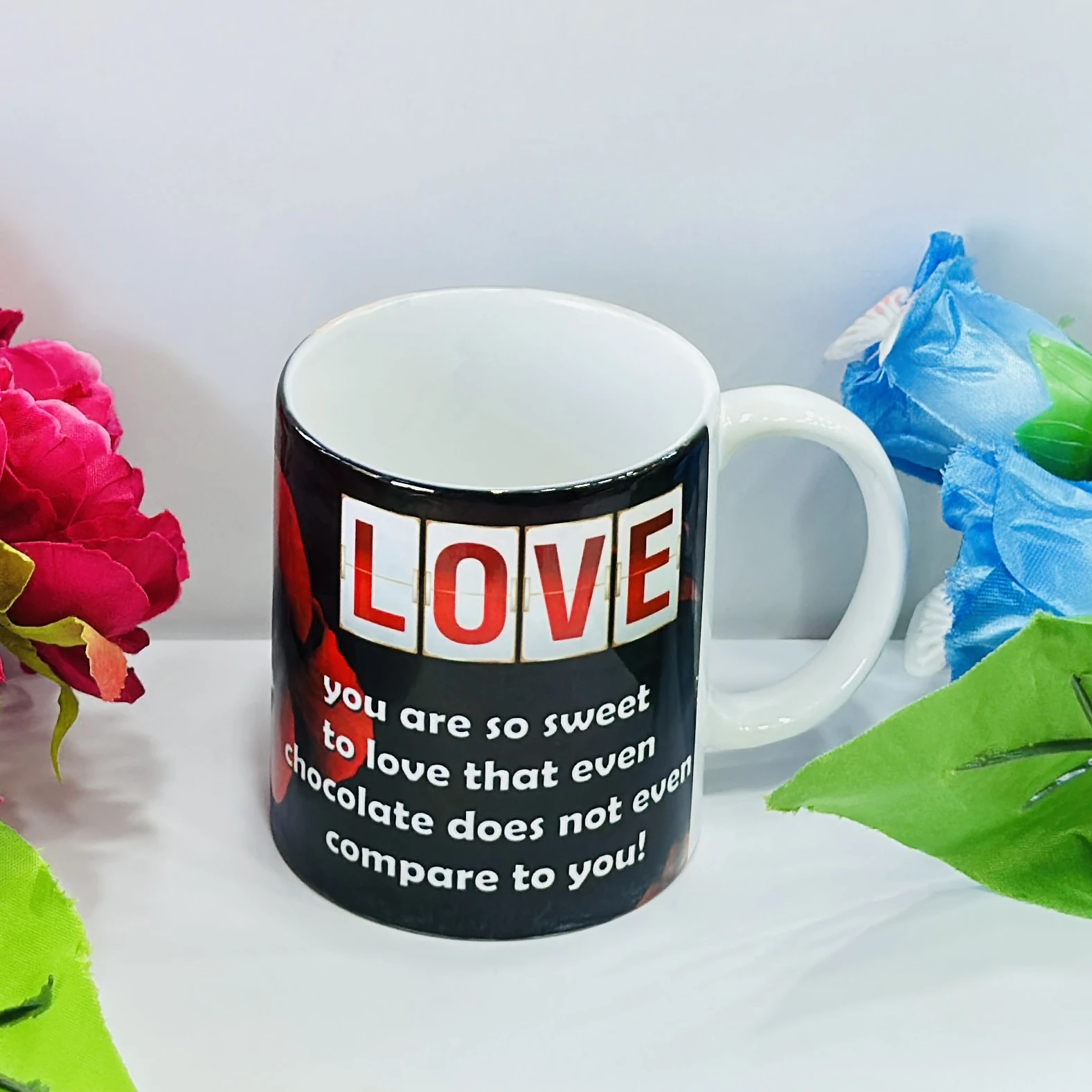 Black ceramic coffee mug with a red rose design.……33J49Y
