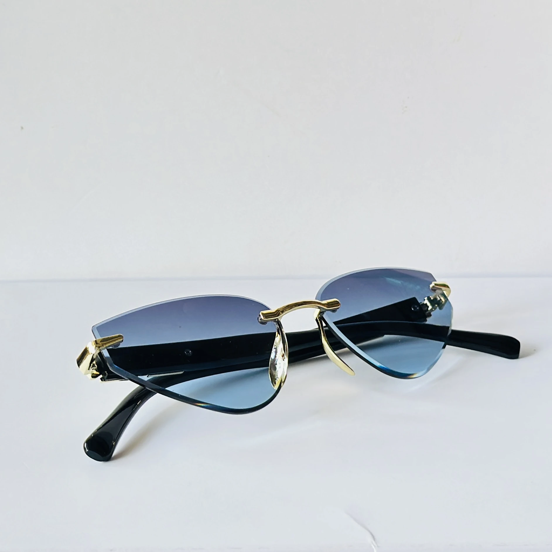 Rimless cat-eye sunglasses feature golden metal frame