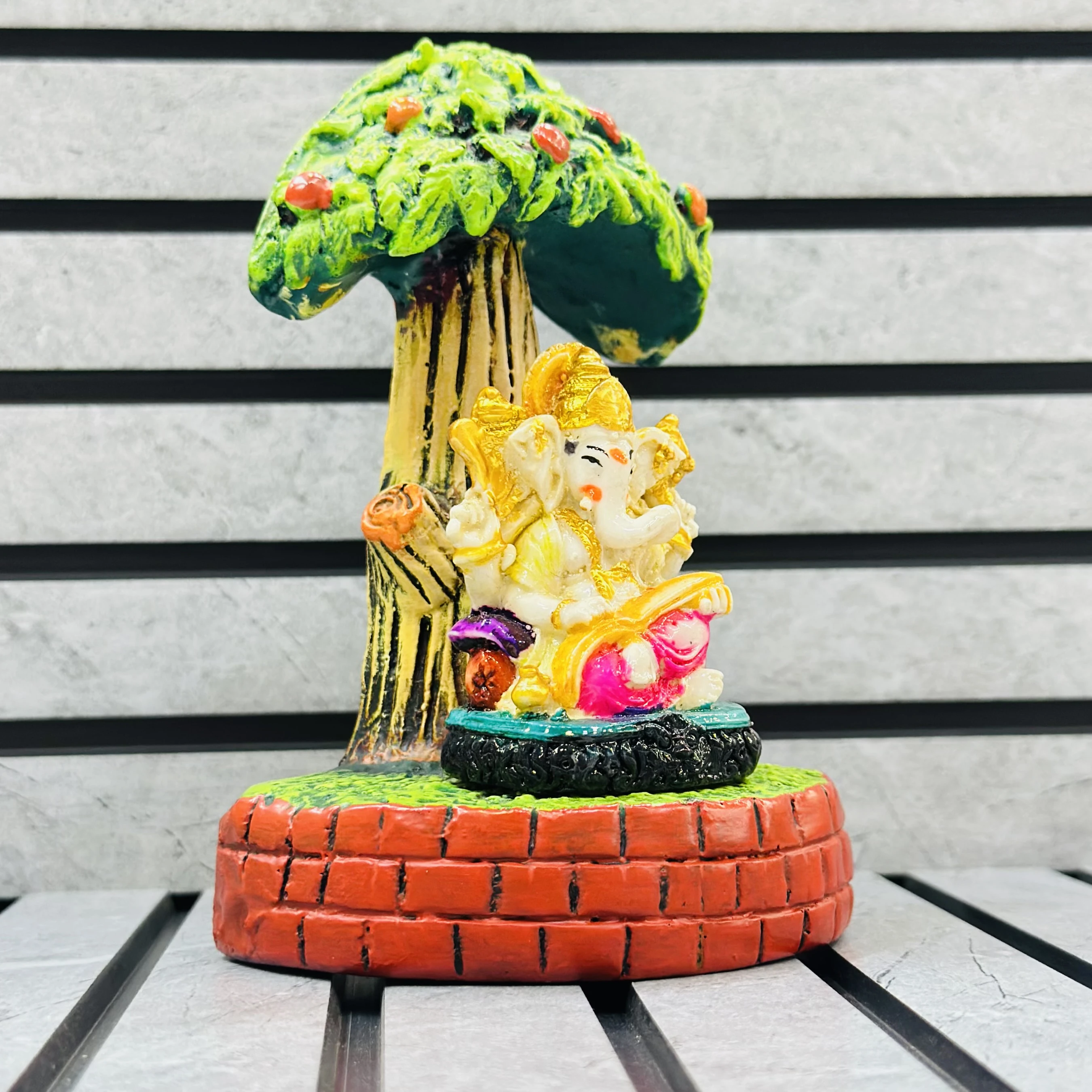 small statue of the Hindu deity Lord Ganesha seated under a tree