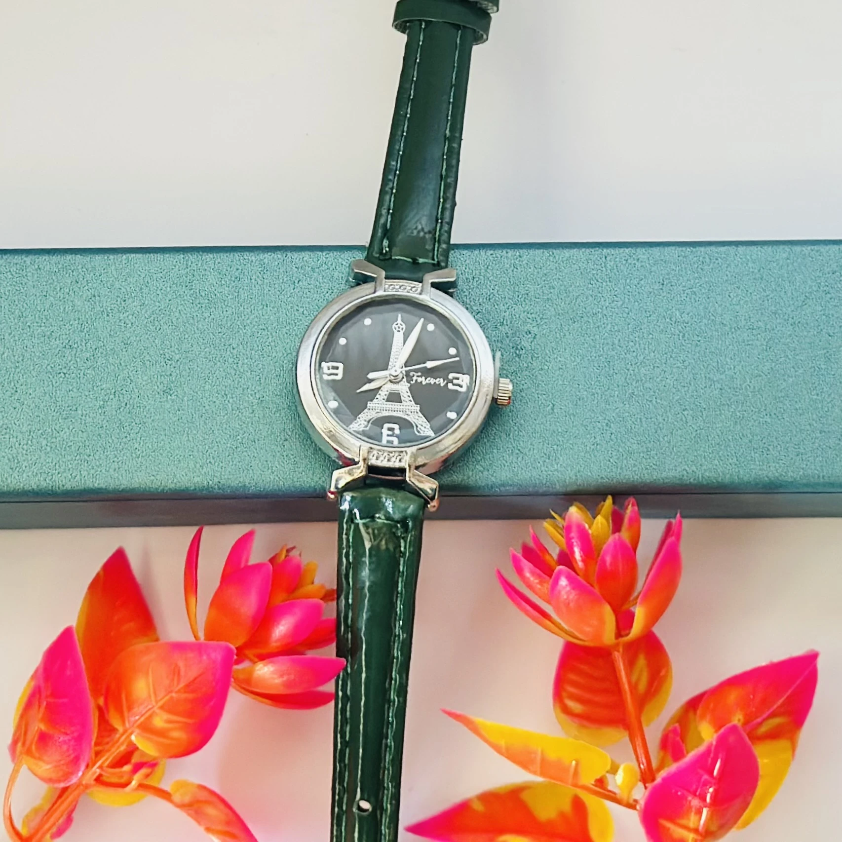 women's analog watch featuring an Eiffel Tower design and a green leather strap.