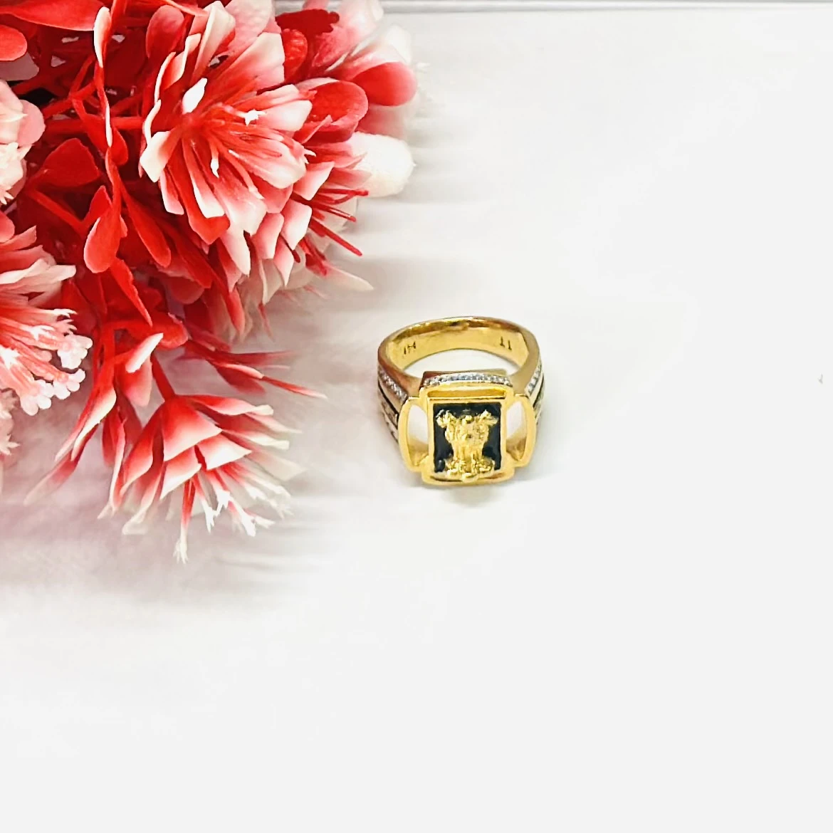 Gold -toned men's signet ring with black accent stones and engraved text.