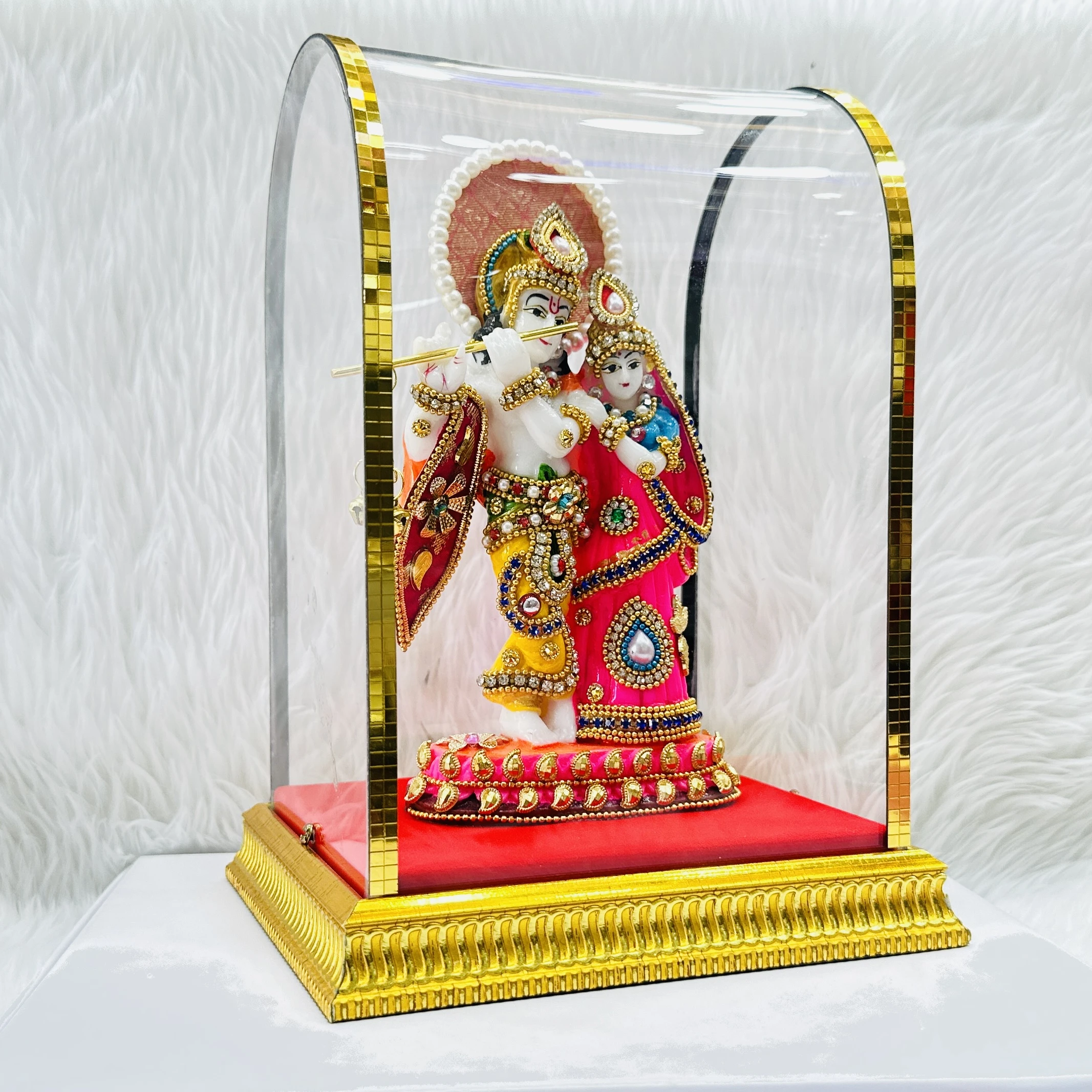 Radha Krishna statue enclosed in a protective glass dome.