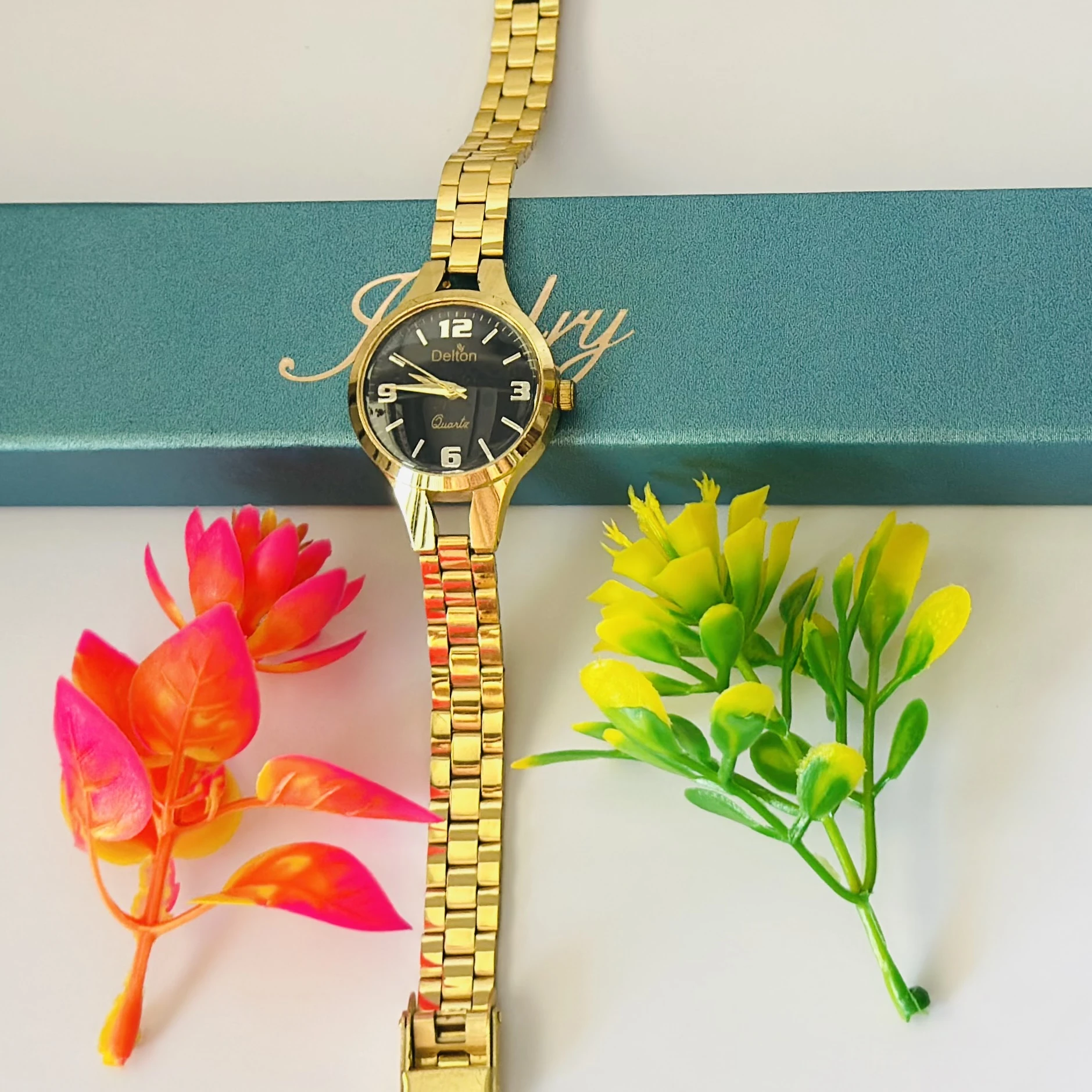 Analog quartz watch with a black dial and a gold-tone stainless steel strap.