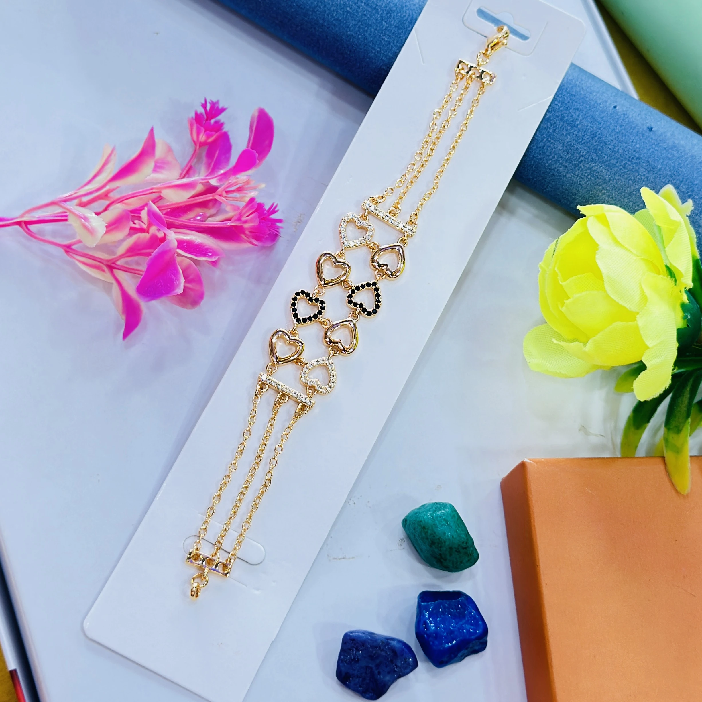Gold plated link bracelet featuring a heart design with inset stones.