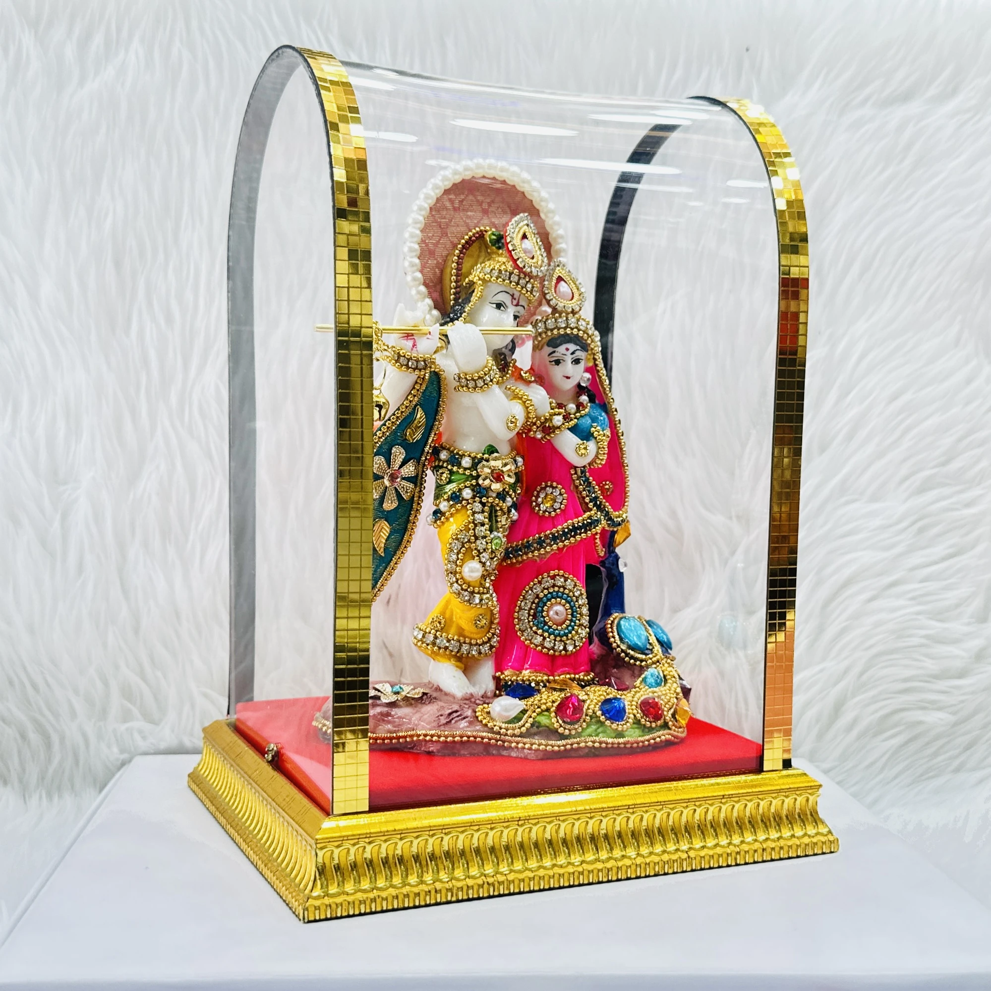 Decorative Radha Krishna statue enclosed in a protective glass dome.