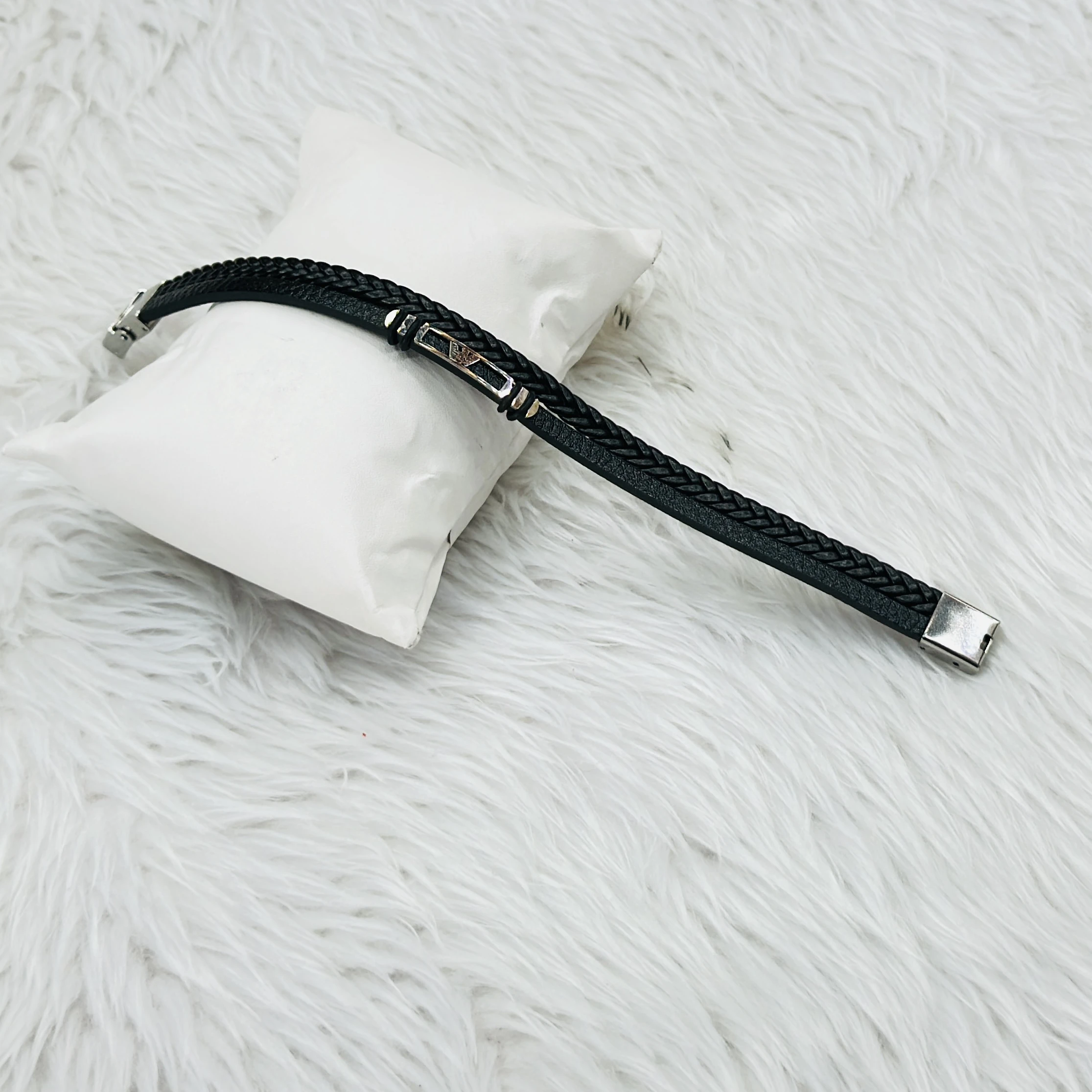 Jewelry bracelet features a black leather design paired with a stainless steel bar.