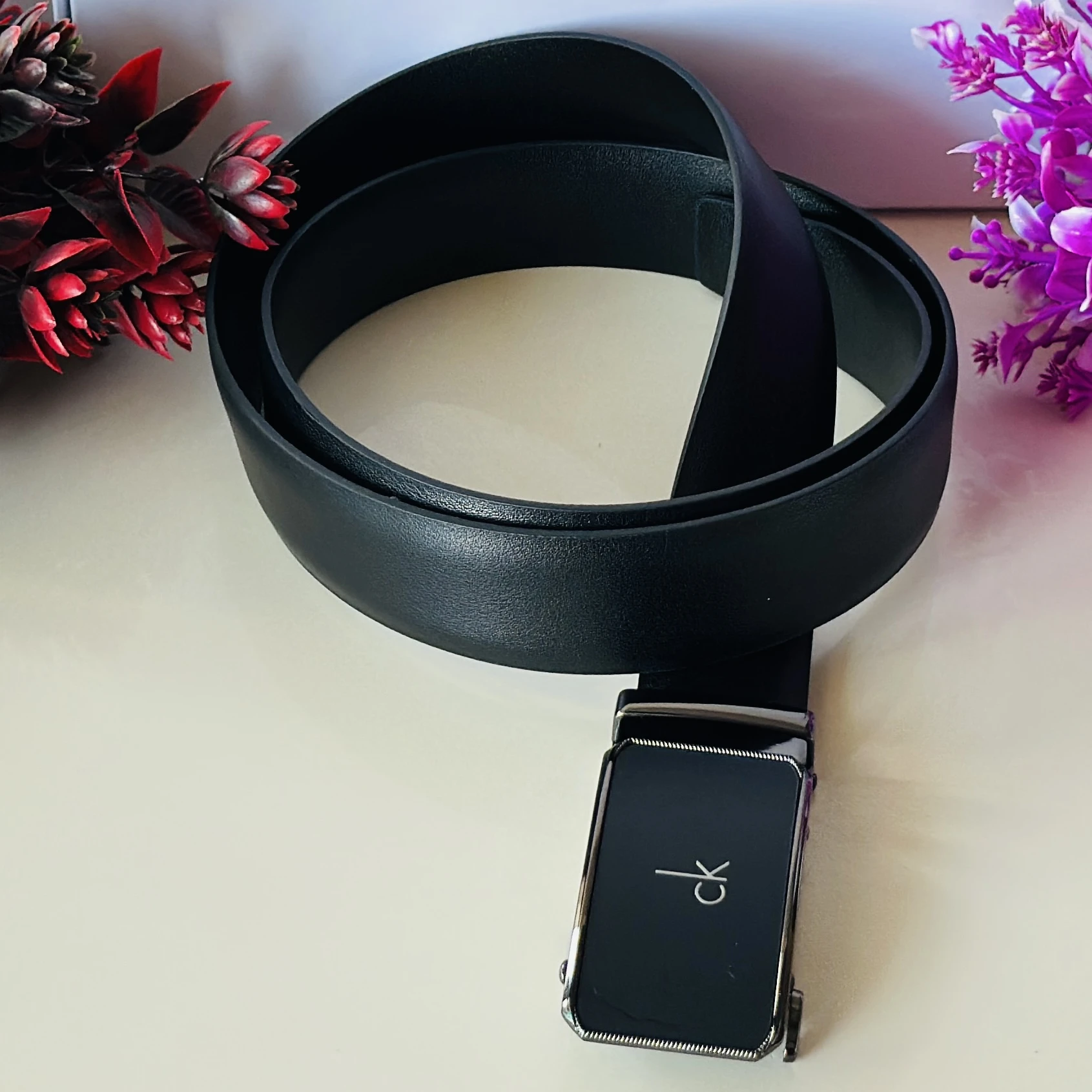 black Calvin Klein leather belt with a metal plaque buckle.