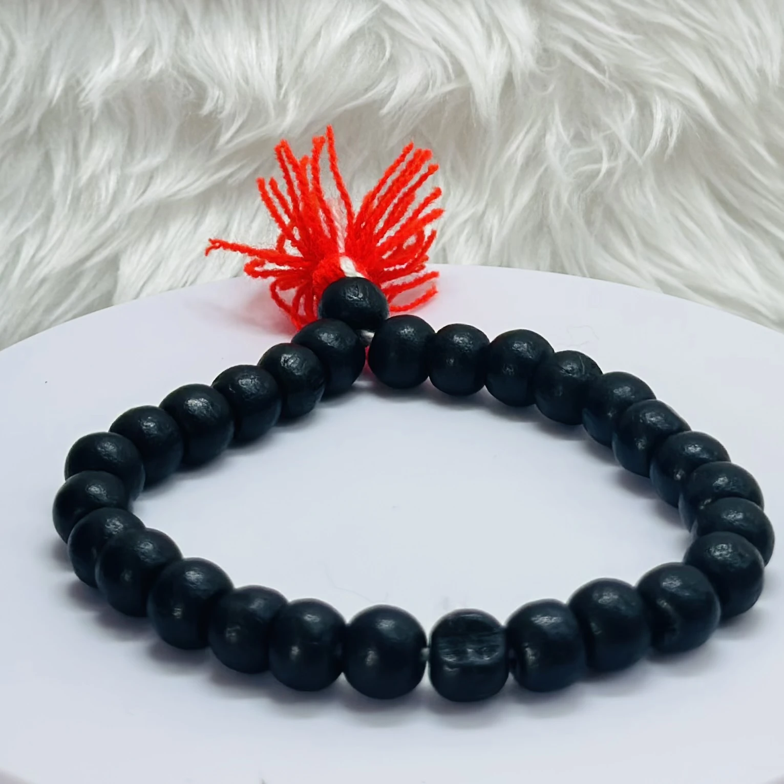 Black onyx or blackwood beaded bracelet with a red tassel.