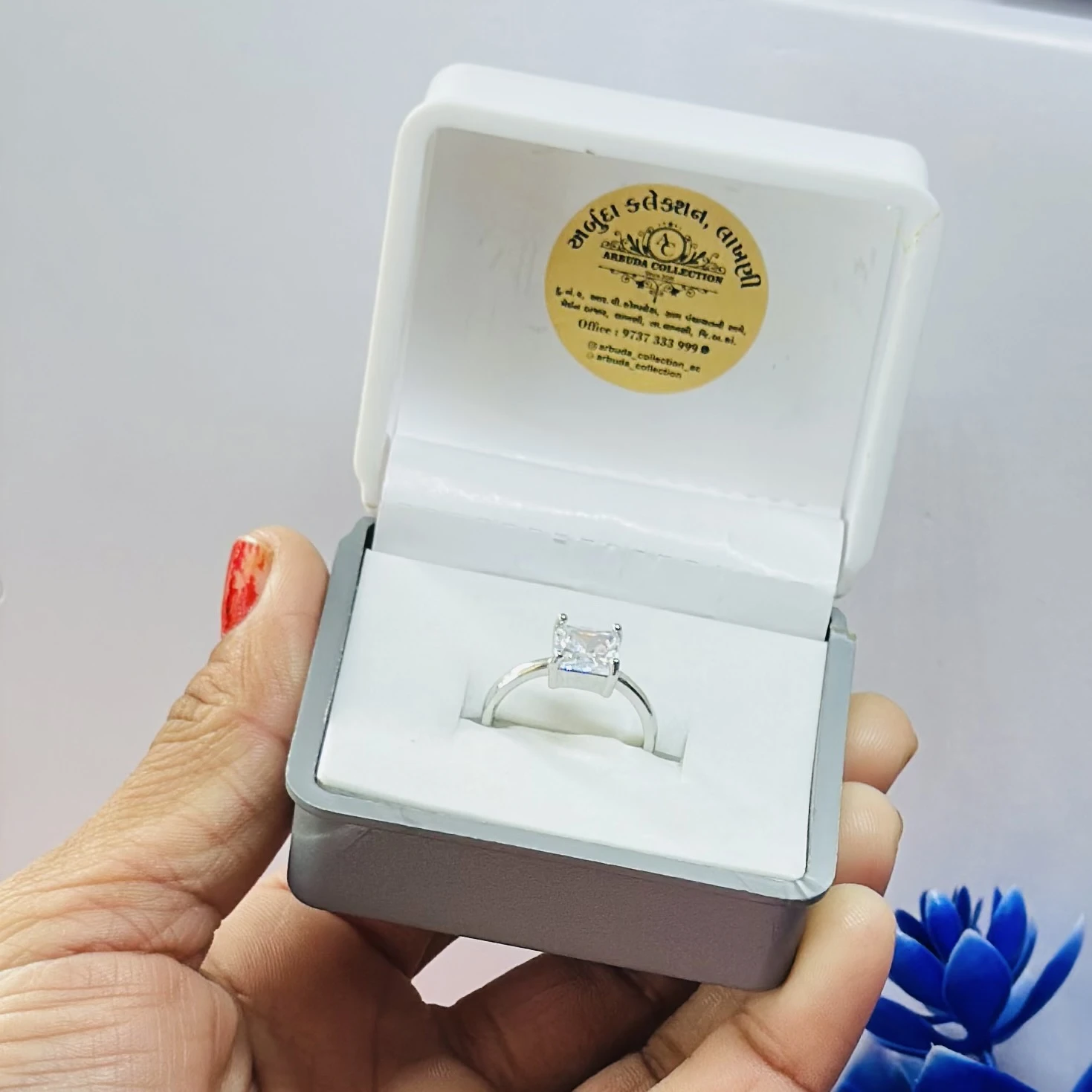princess-cut solitaire engagement ring, possibly a moissanite set in white metal.