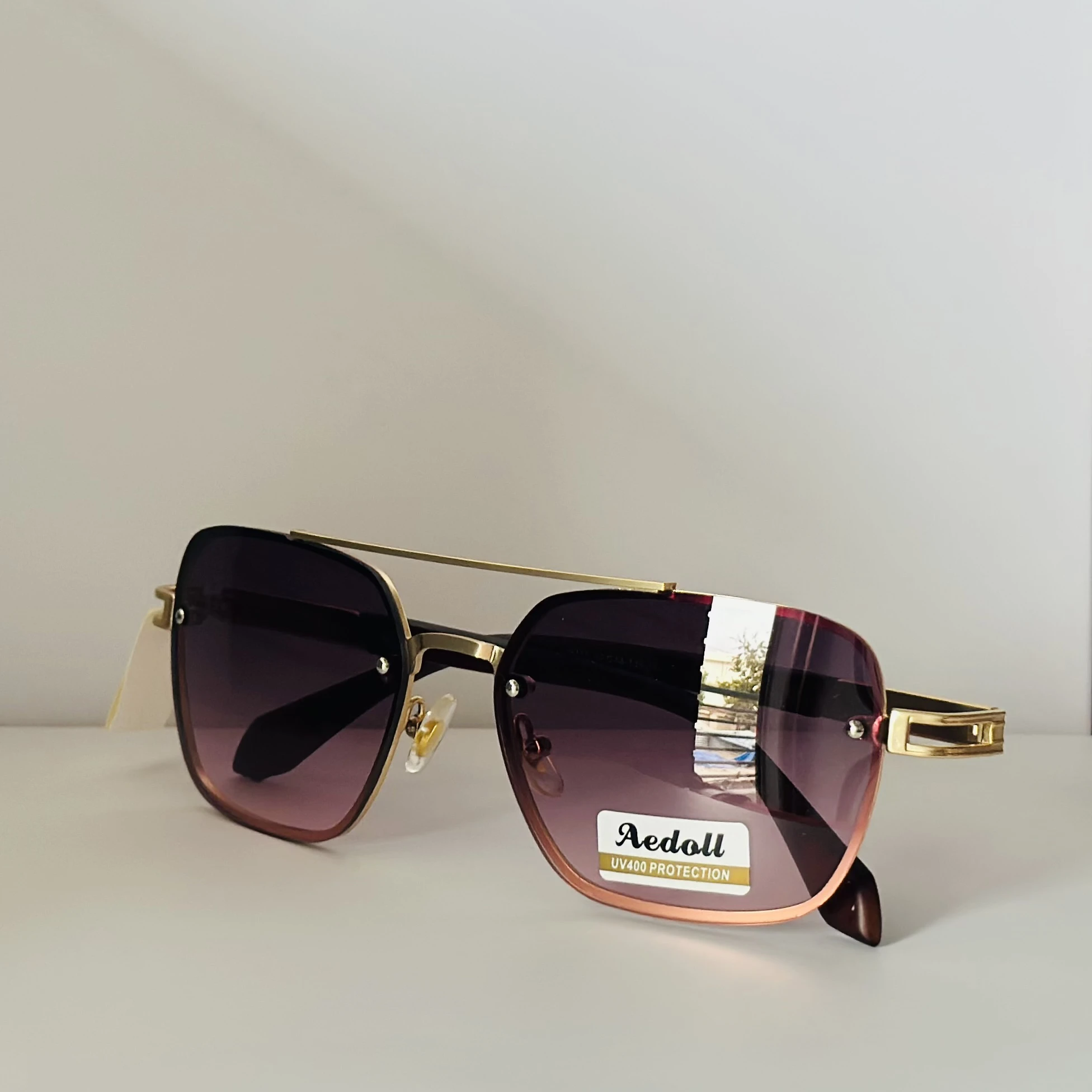 pair of Aedoll Goggle sunglasses with a gold metal frame and pink gradient lenses.