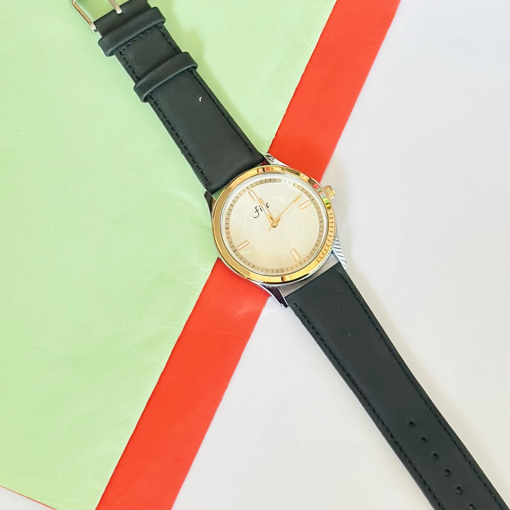 Analog wristwatch with a gold-tone case and a black leather strap.