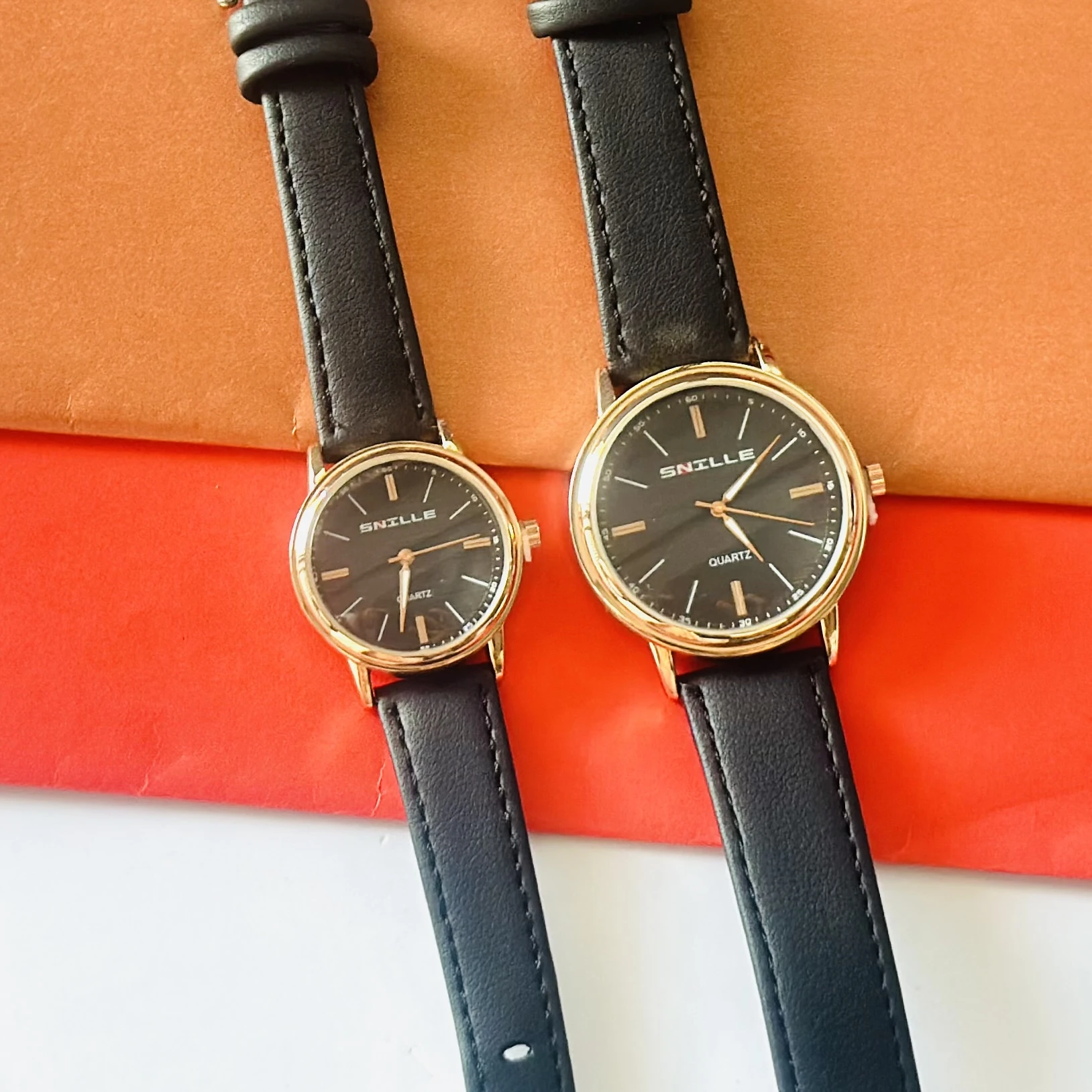 black "Snille" quartz watches with gold-tone cases and black faux leather straps