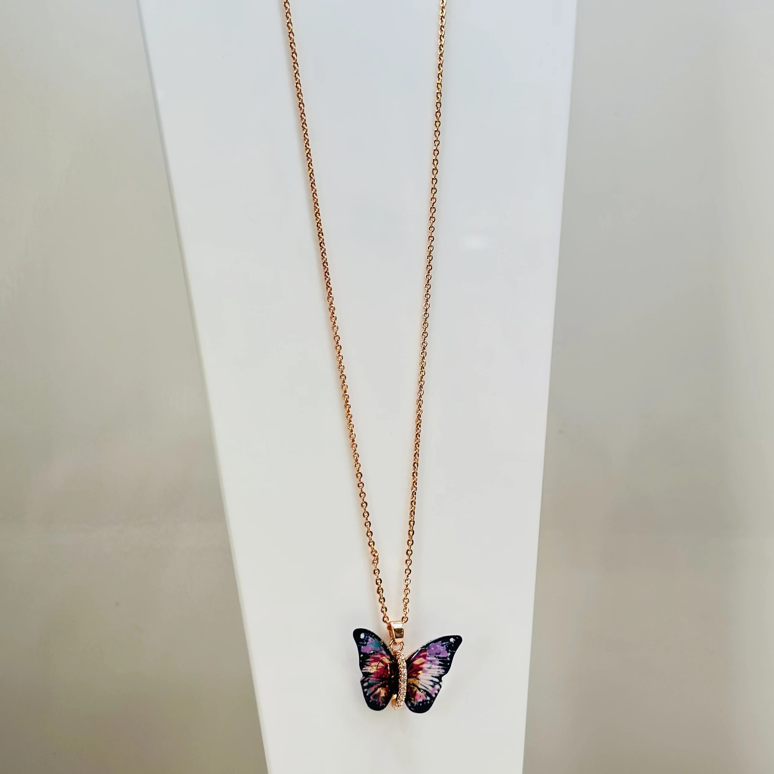 Rose gold-toned with a colorful butterfly pendant featuring a rhinestone accent