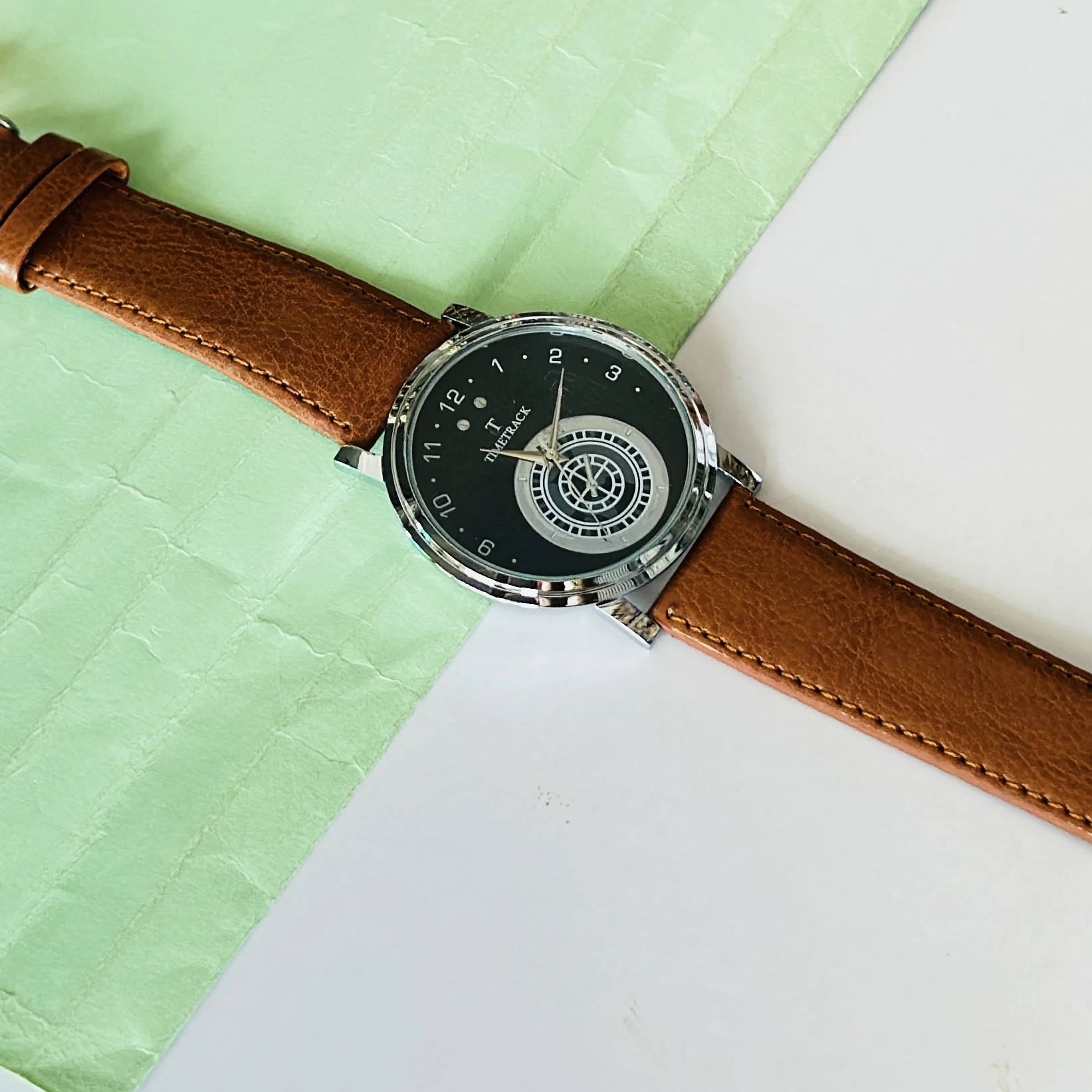 quartz analog watch with a brown leather strap and a black dial