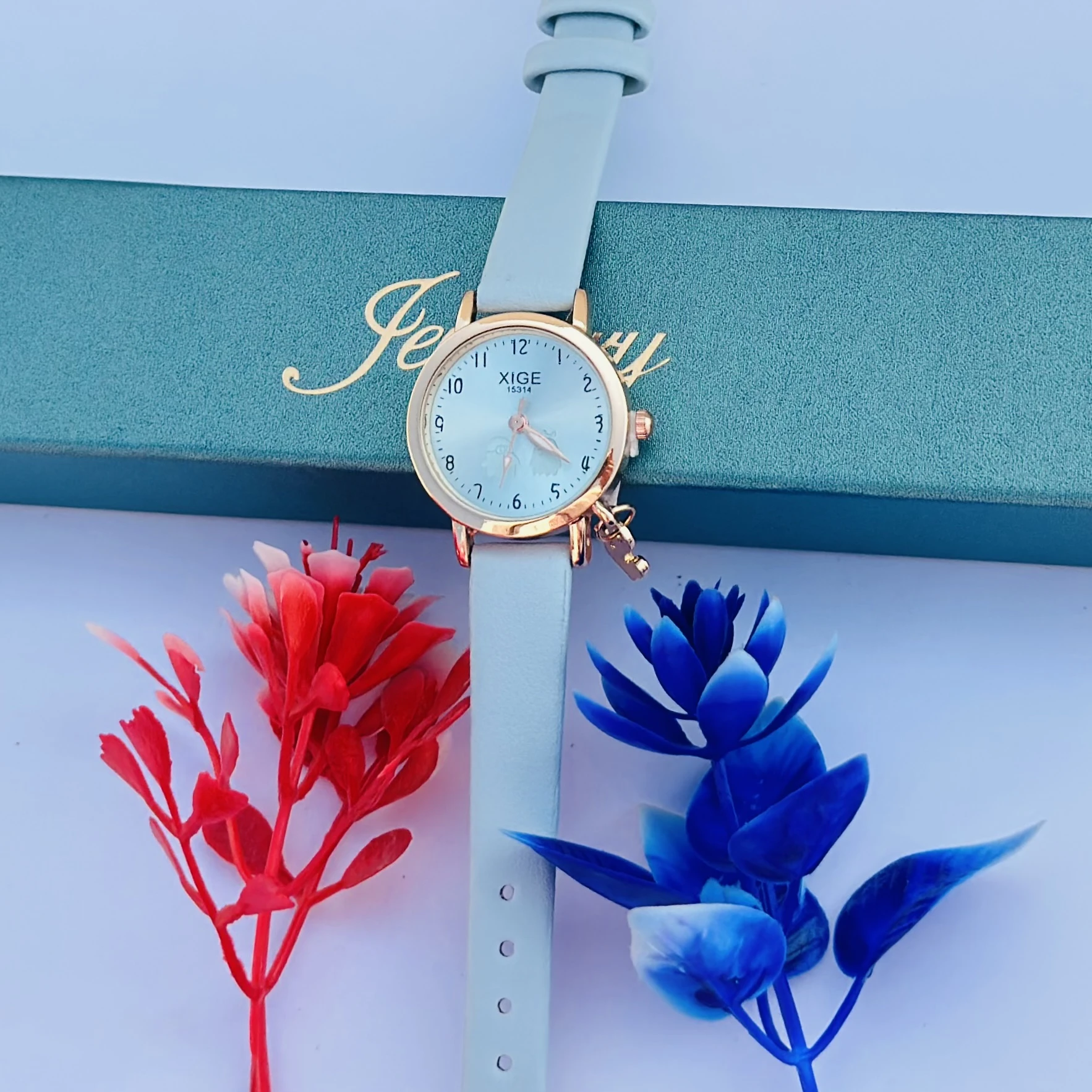 analog quartz watch with a rose gold case and a light blue leather strap featuring a horse charm.