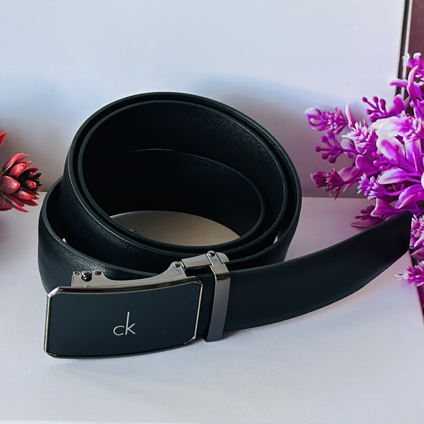 black Calvin Klein leather belt with a metal plaque buckle.