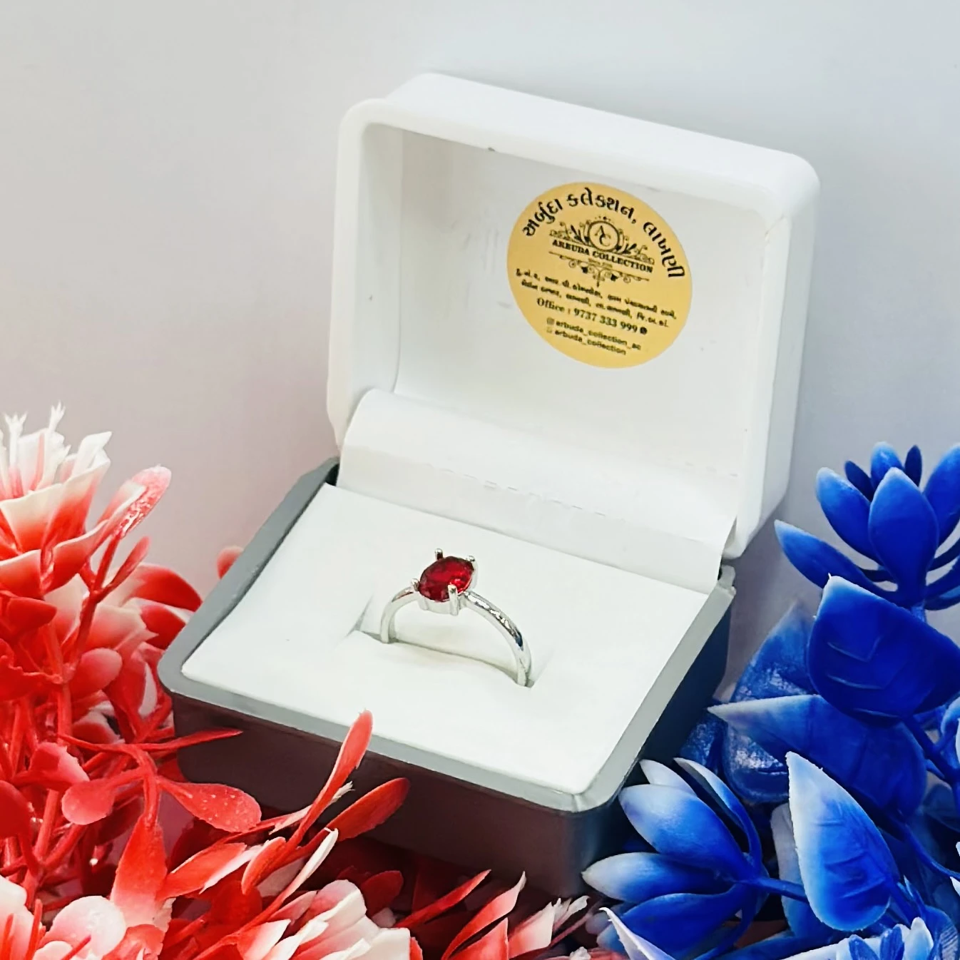 white gold or silver solitaire ring with an oval-cut ruby gemstone.