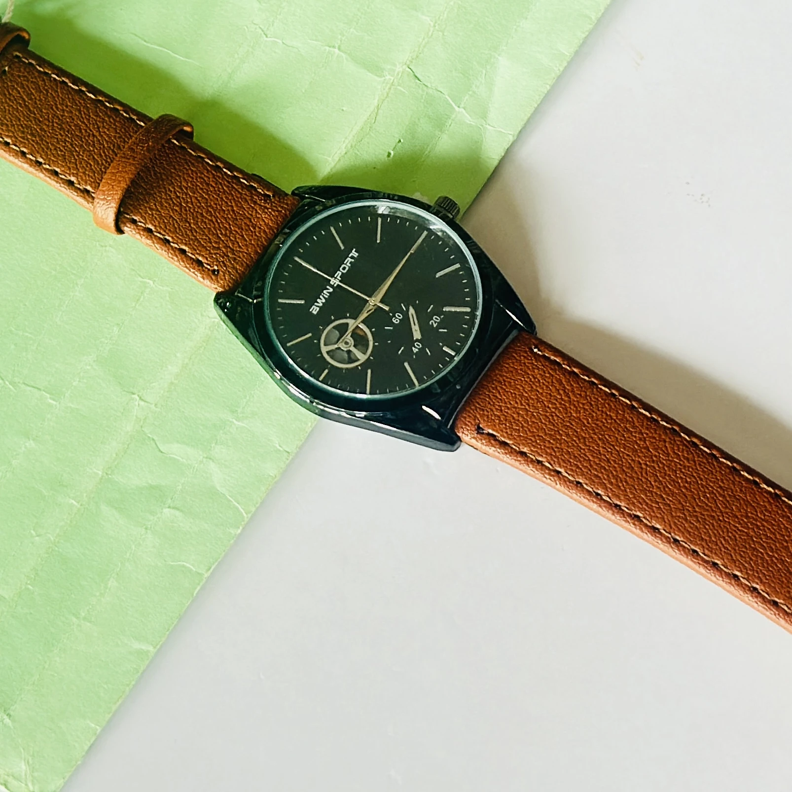 Carlington analog watch with a brown faux leather strap and a black dial.