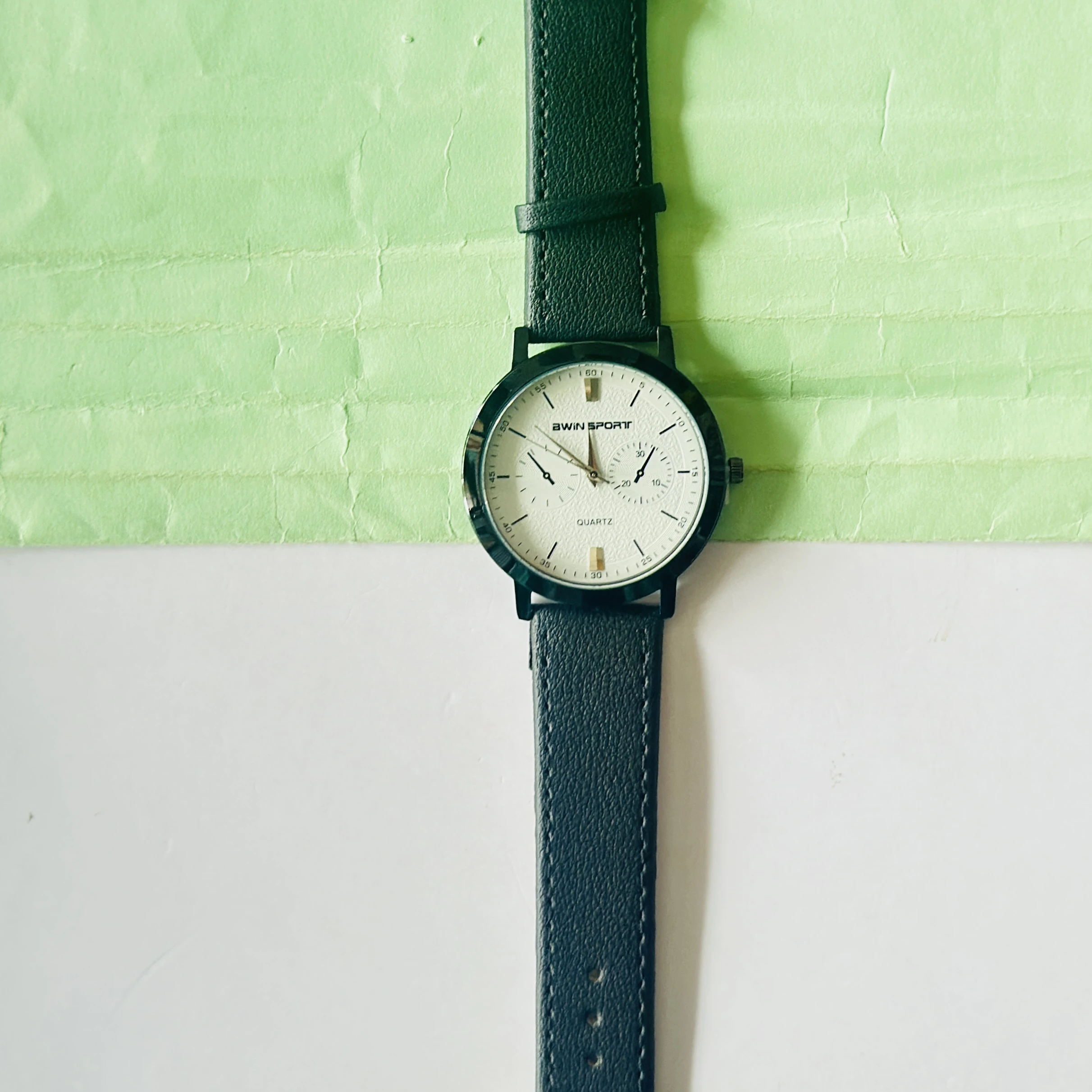 Quartz’s wristwatch featuring a white dial, black markers, and a matching black leather strap.