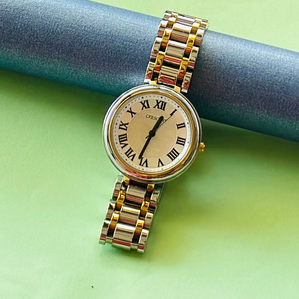 Crescent analog watch with a rectangular case and a two-tone (silver and gold) metal bracelet.