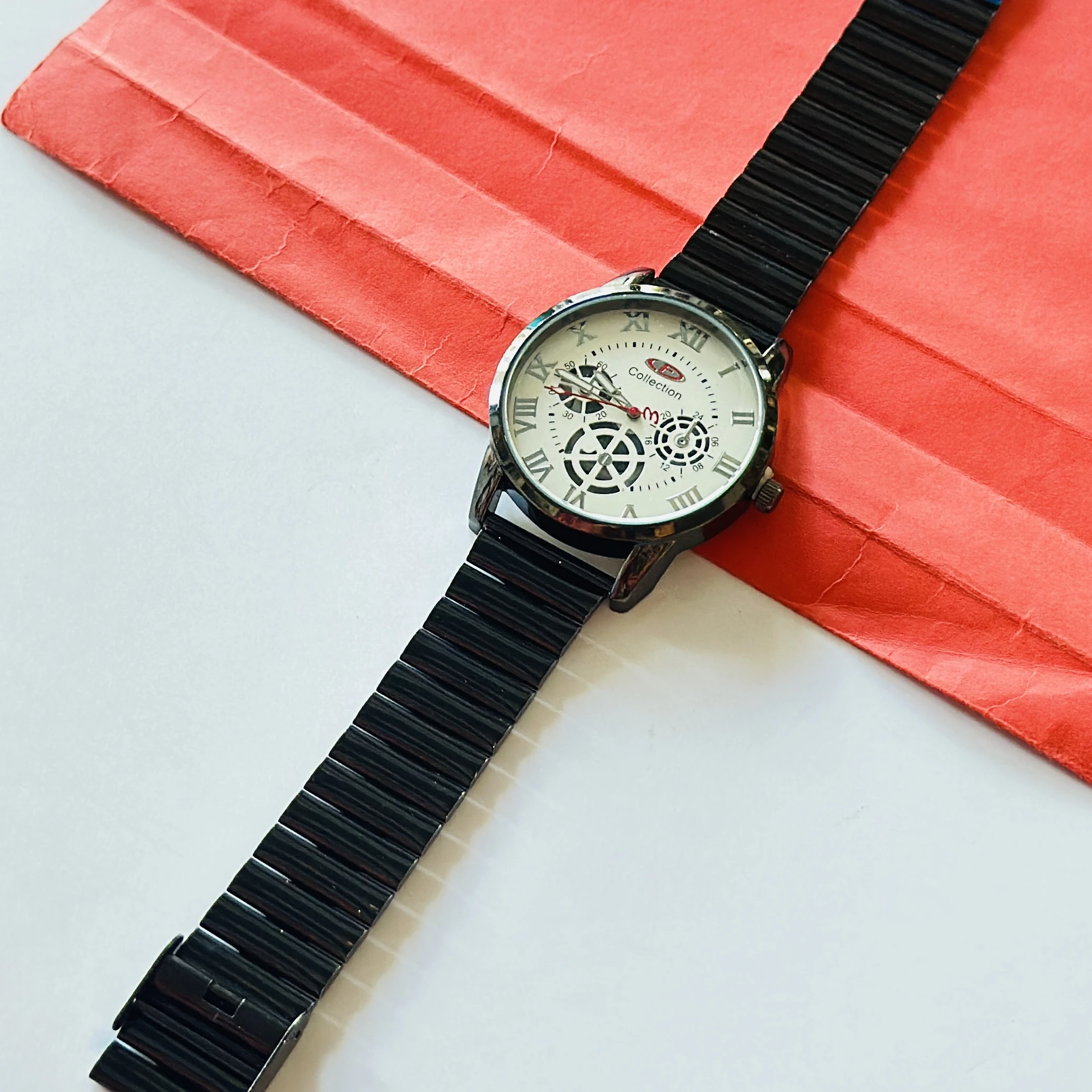 Black metal analog wristwatch with a white dial and roman numeral markers.