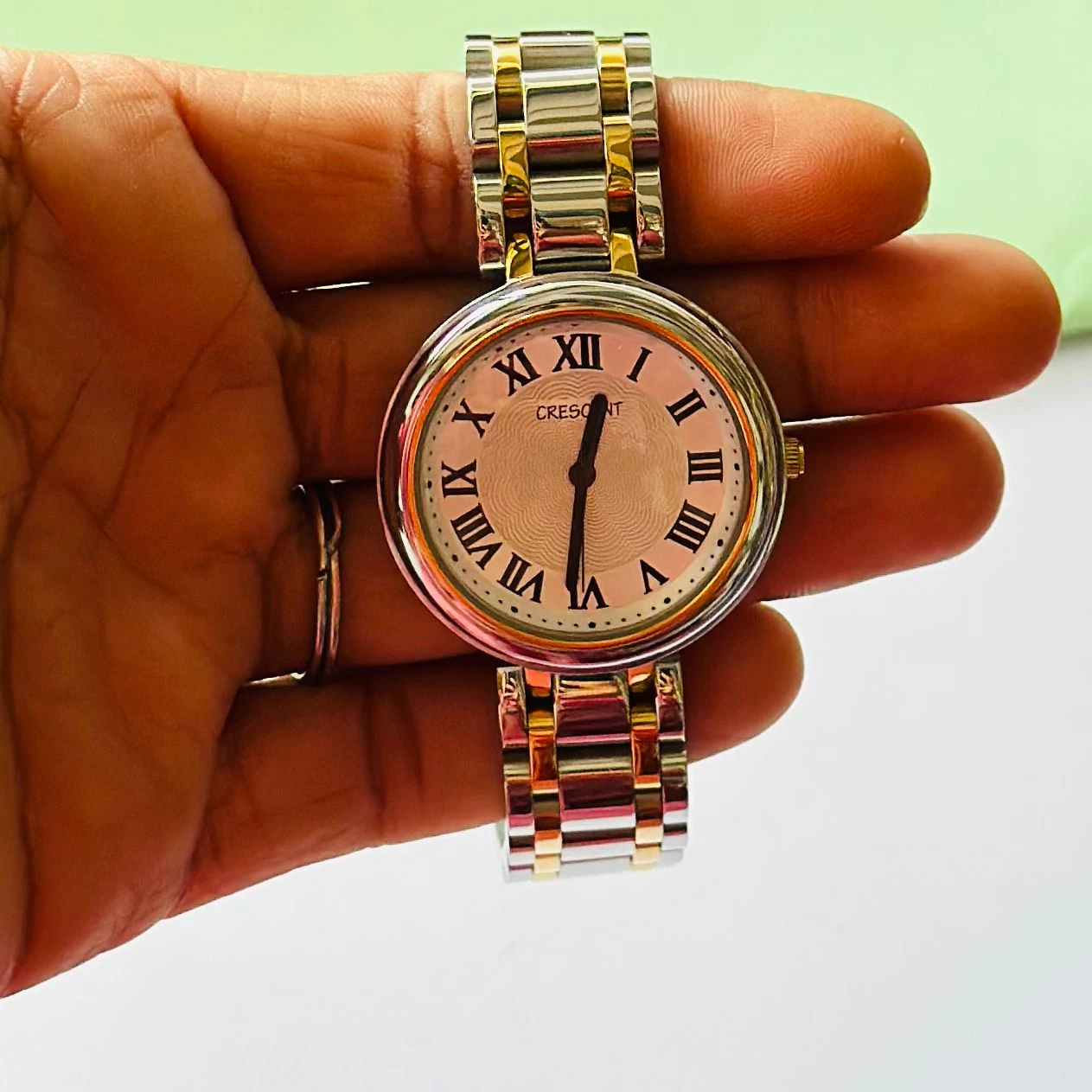 Crescent analog watch with a rectangular case and a two-tone (silver and gold) metal bracelet.