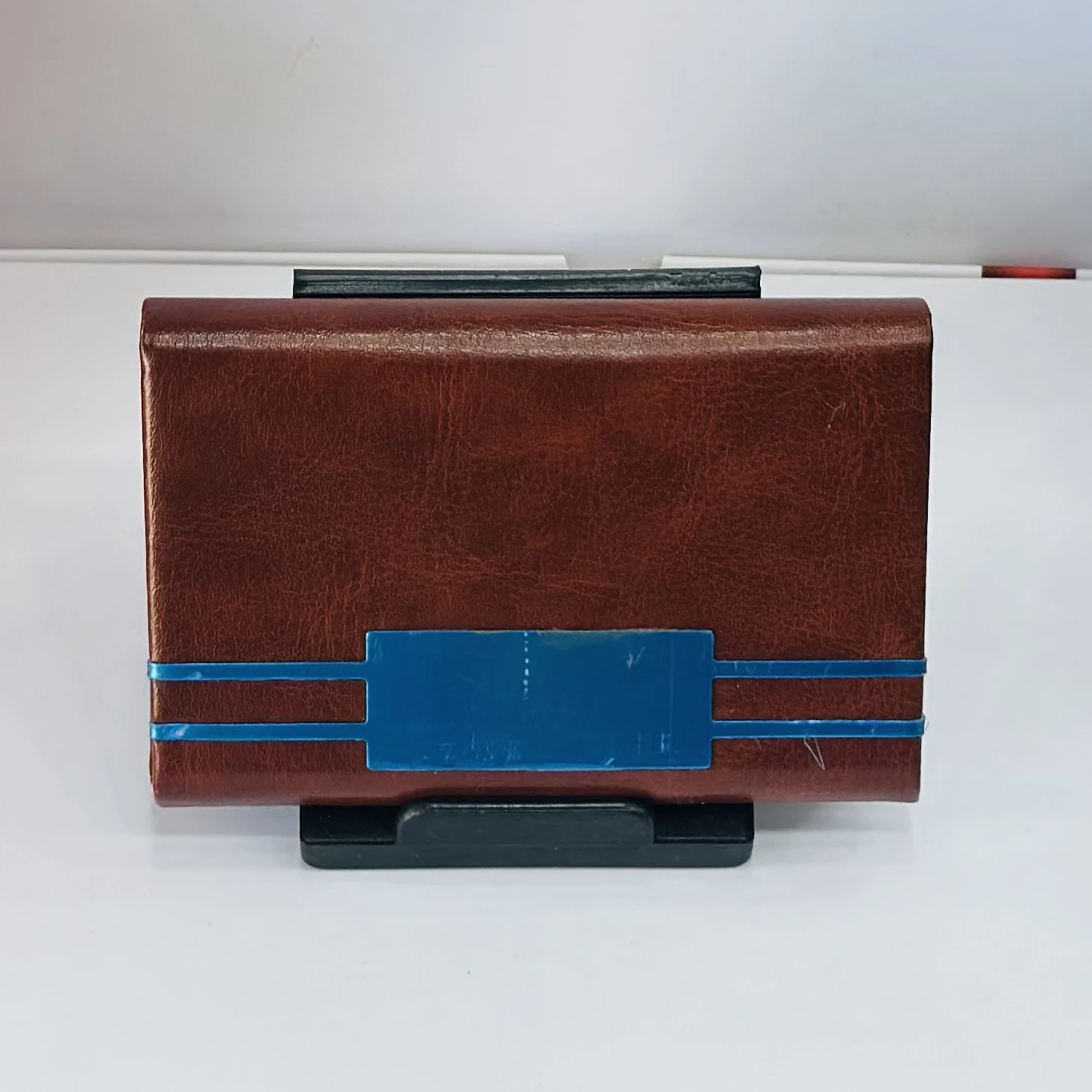 brown leather business card holder with blue metal accents.