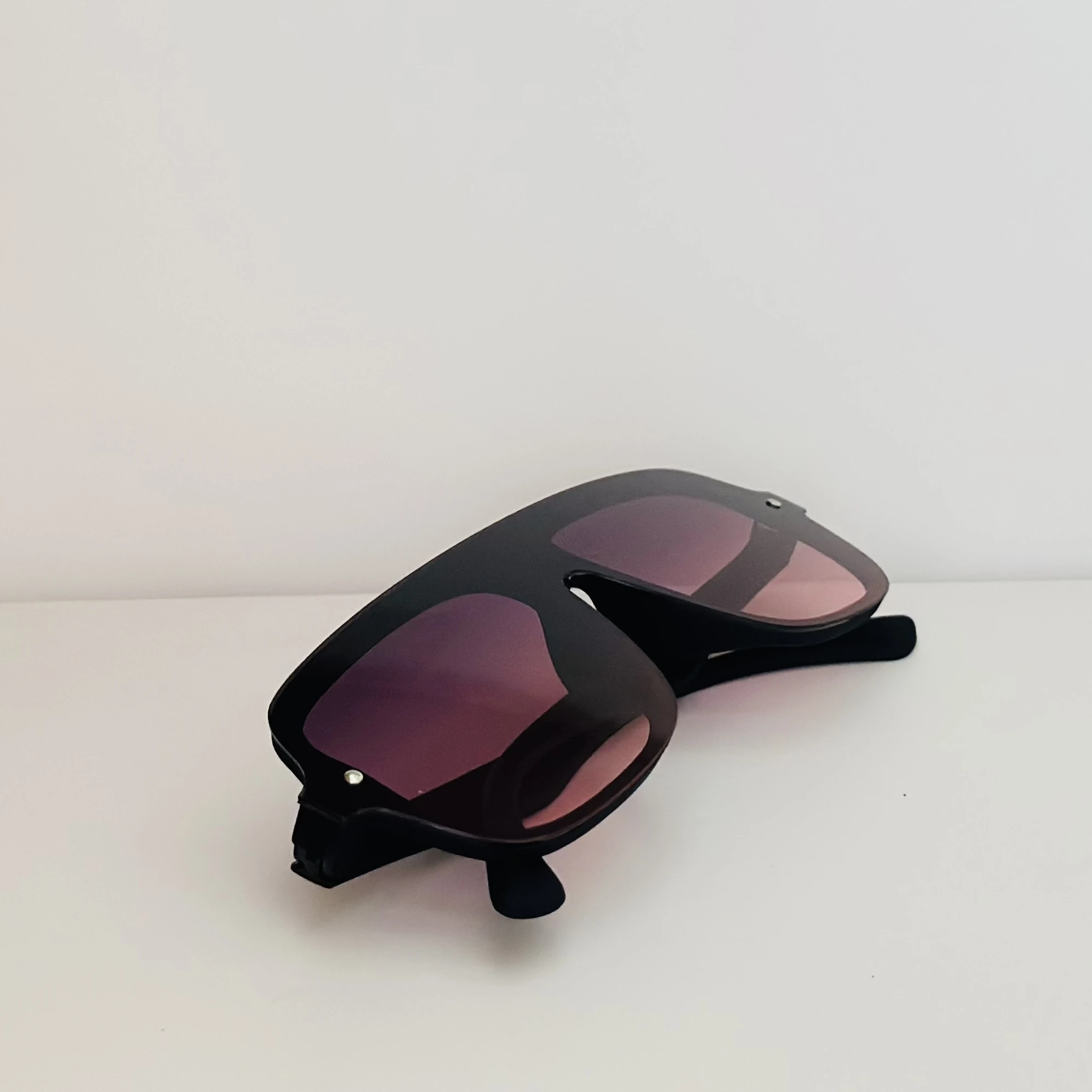 Black frame aviator-style sunglasses with pink gradient lenses.