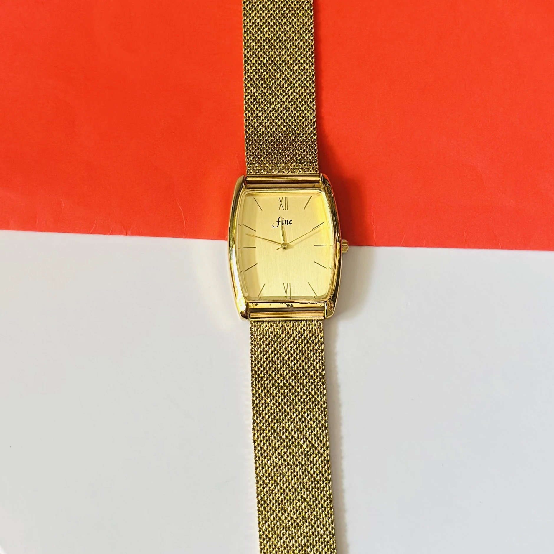 Gold -plated quartz analogue watch with a mesh strap.