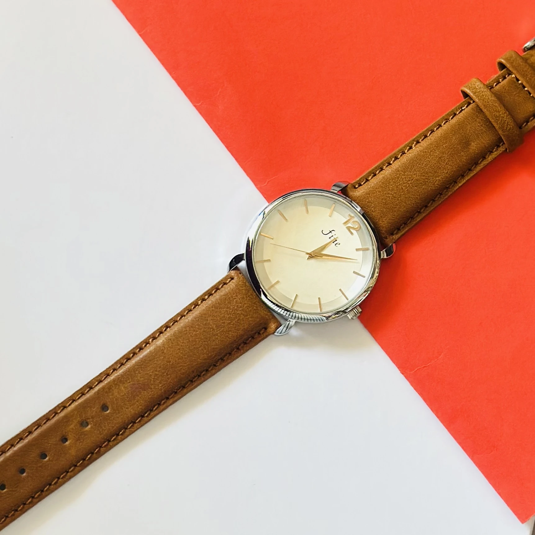 minimalist analog watch with a white dial, gold-tone case, and a brown leather strap