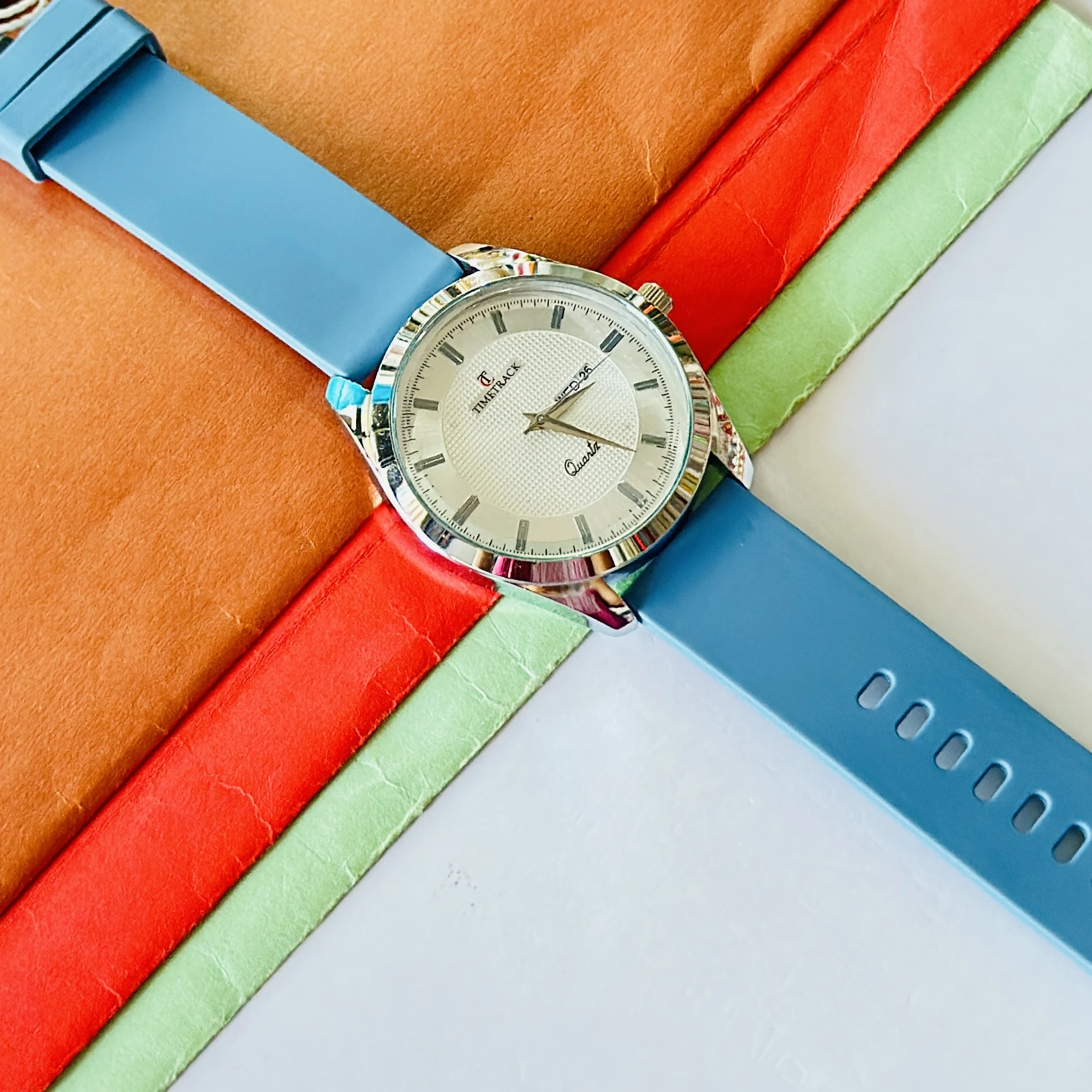 Timetrack quartz analog watch with a white textured dial and a blue silicone strap.