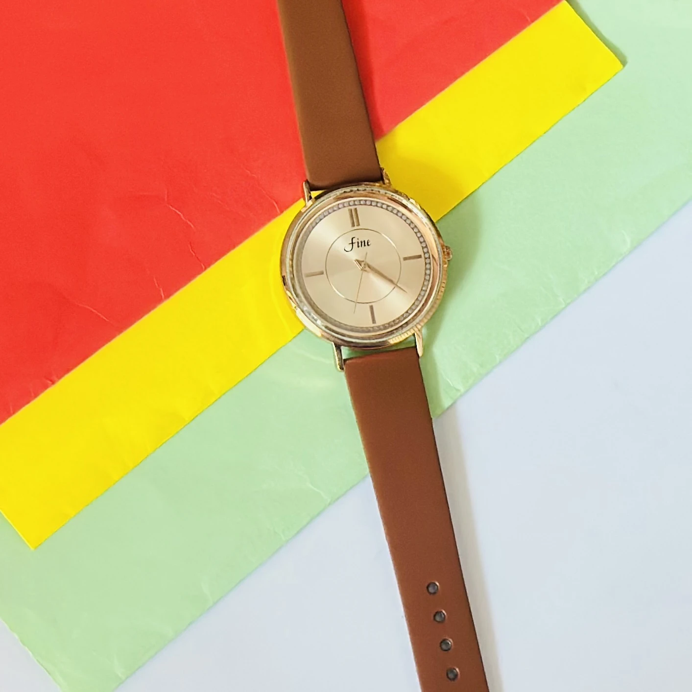 Gold tone analog wrist watch with a brown leather strap