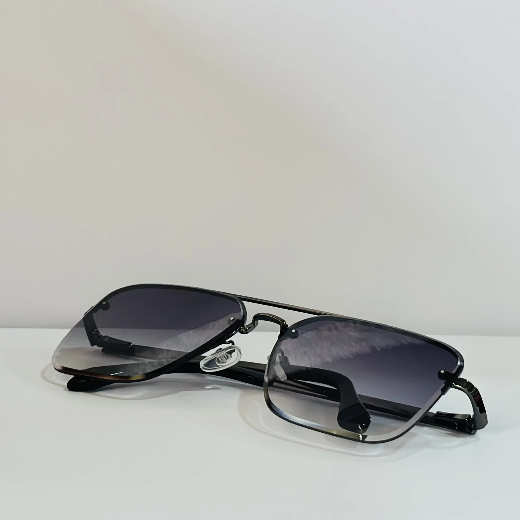 pair of aviator-style sunglasses with a black metal frame and grey gradient lenses.
