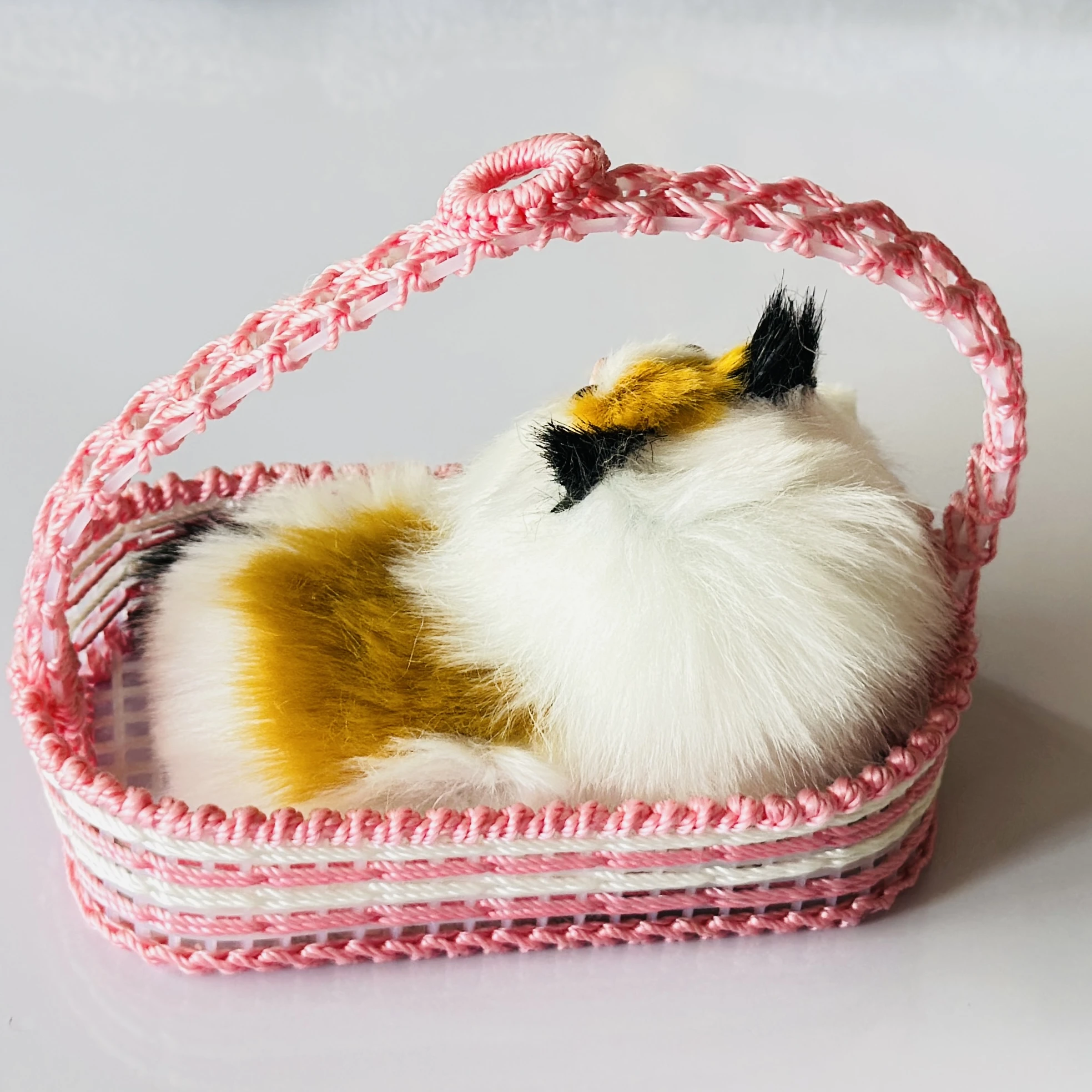 Decorative showpiece featuring a plush cat sitting inside a pink woven basket