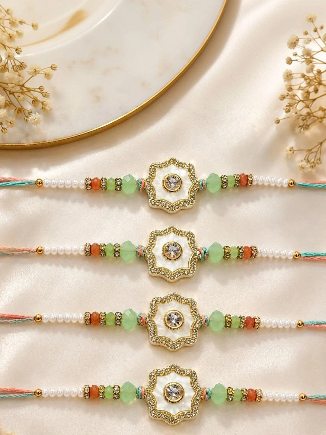 RHOSYN floral rakhi features a white and gold centerpiece with pastel green beads on an adjustable thread.
