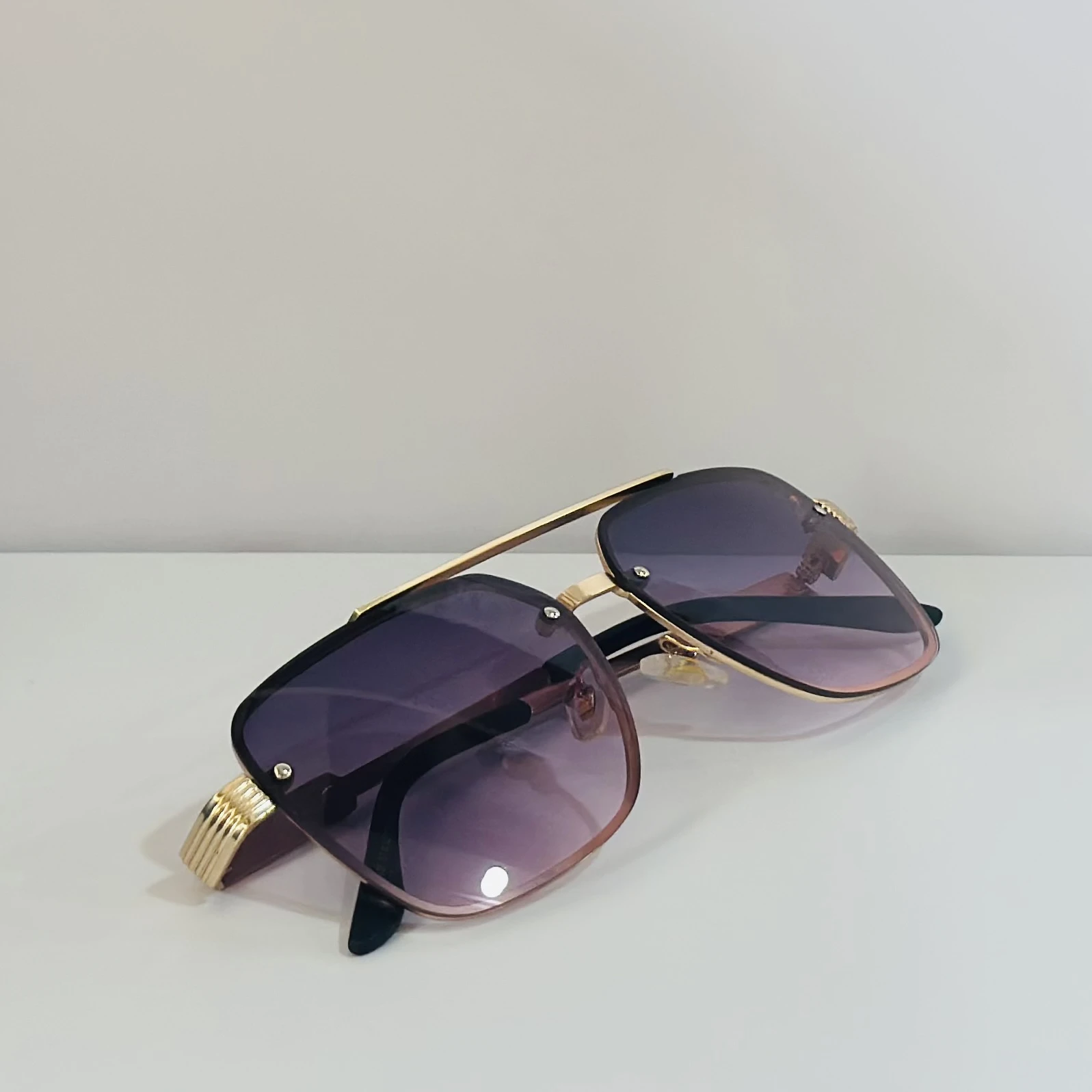 pair of fashionable sunglasses with a gold frame and purple gradient lenses.