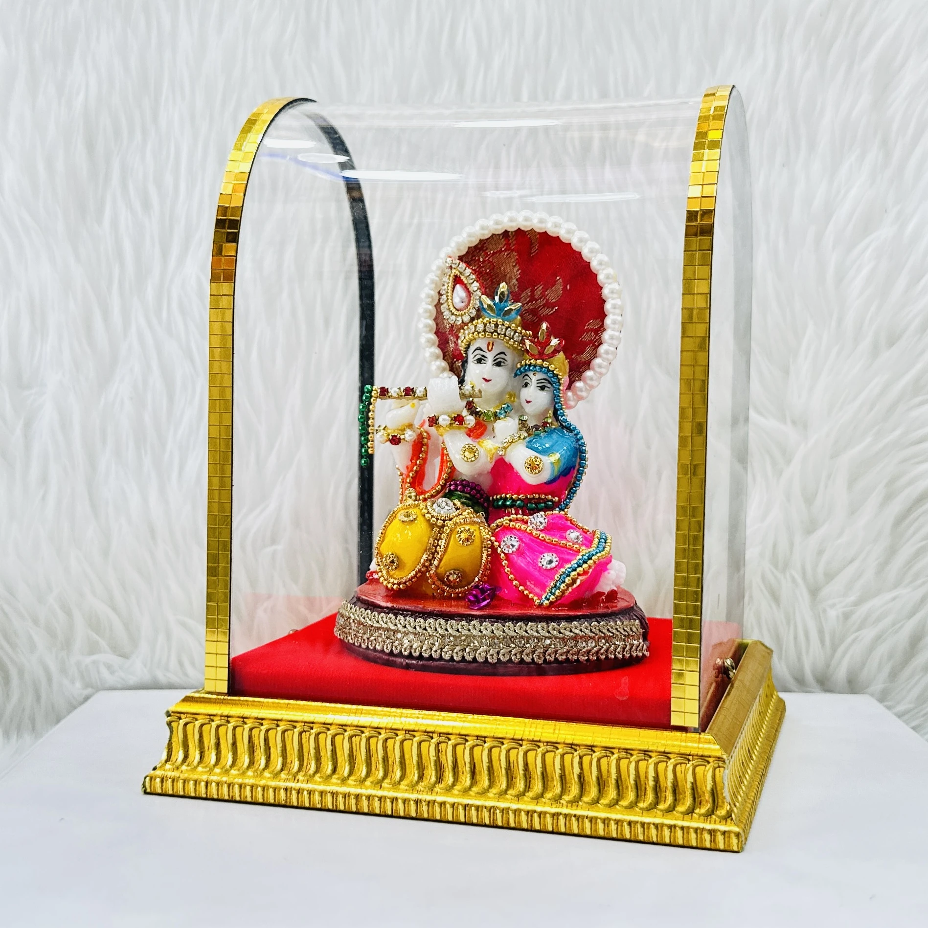 Radha Krishna statue enclosed in a protective glass case.