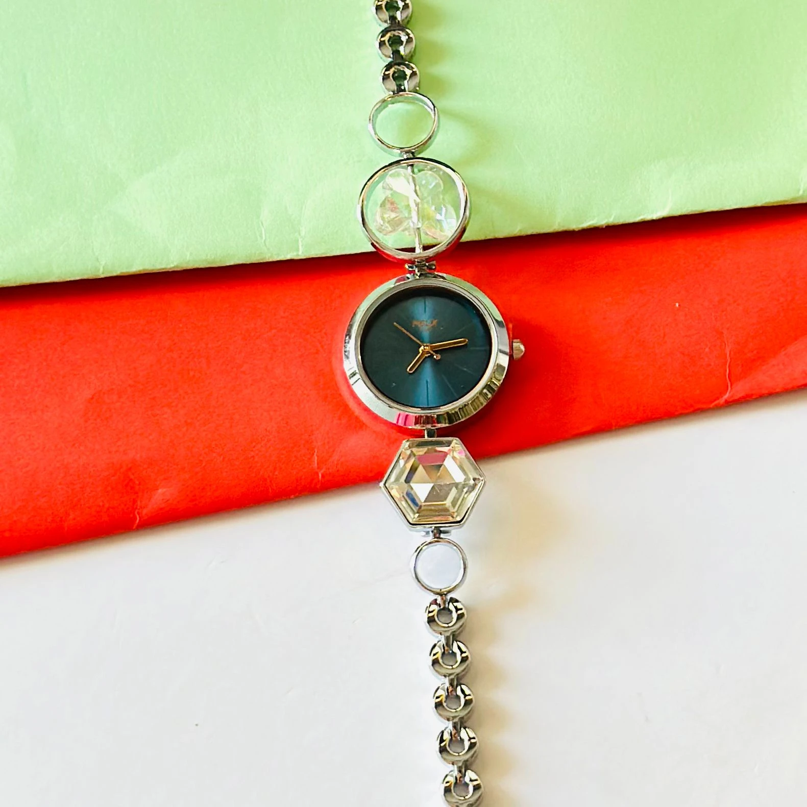 analog watch for women with a blue dial and a metal strap featuring crystal-studded geometric links.