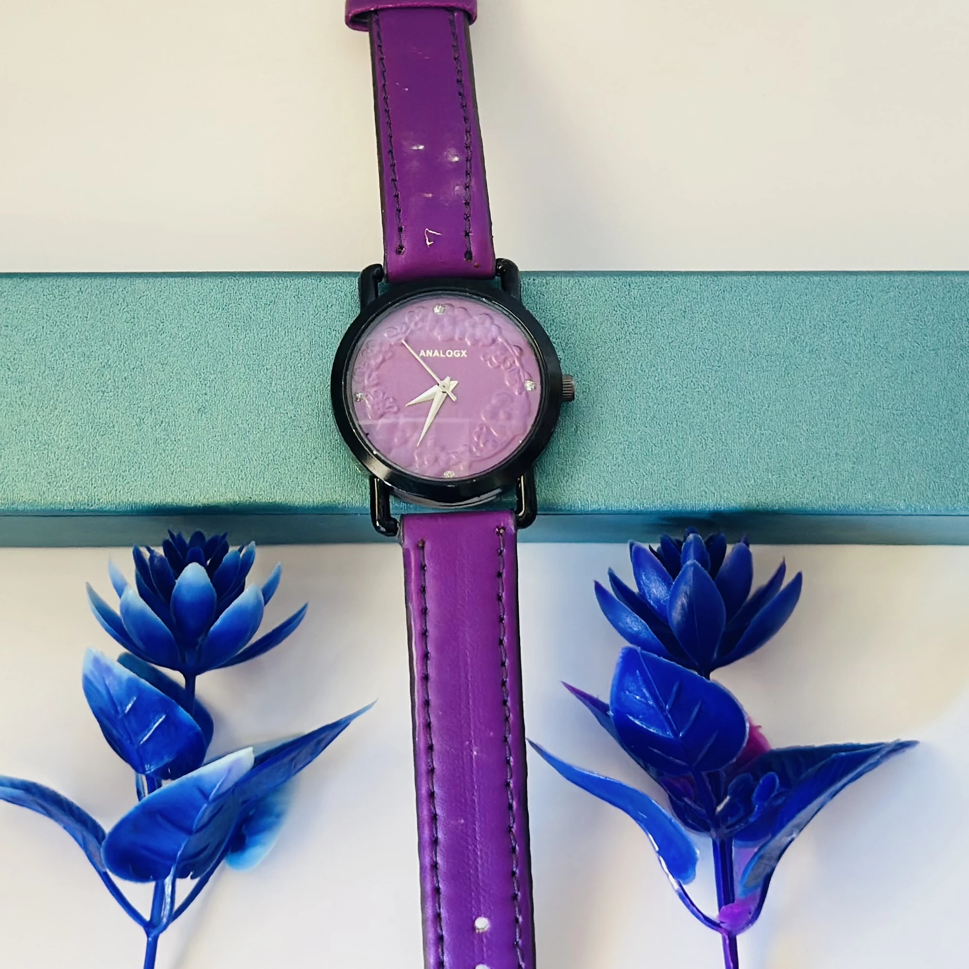 purple analog watch with a black leather strap.