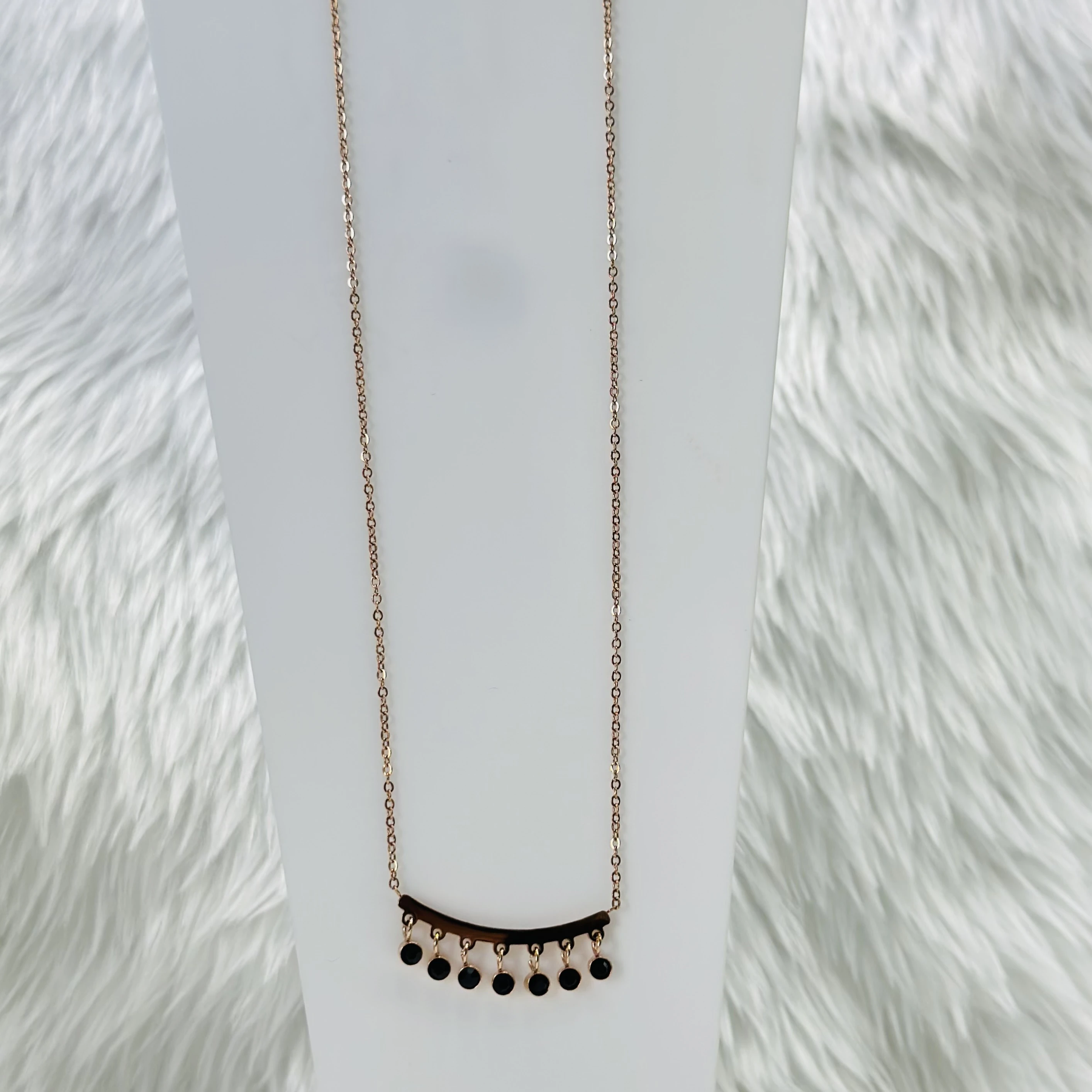 Mangalsutra necklace with a curved bar pendant and black beads.