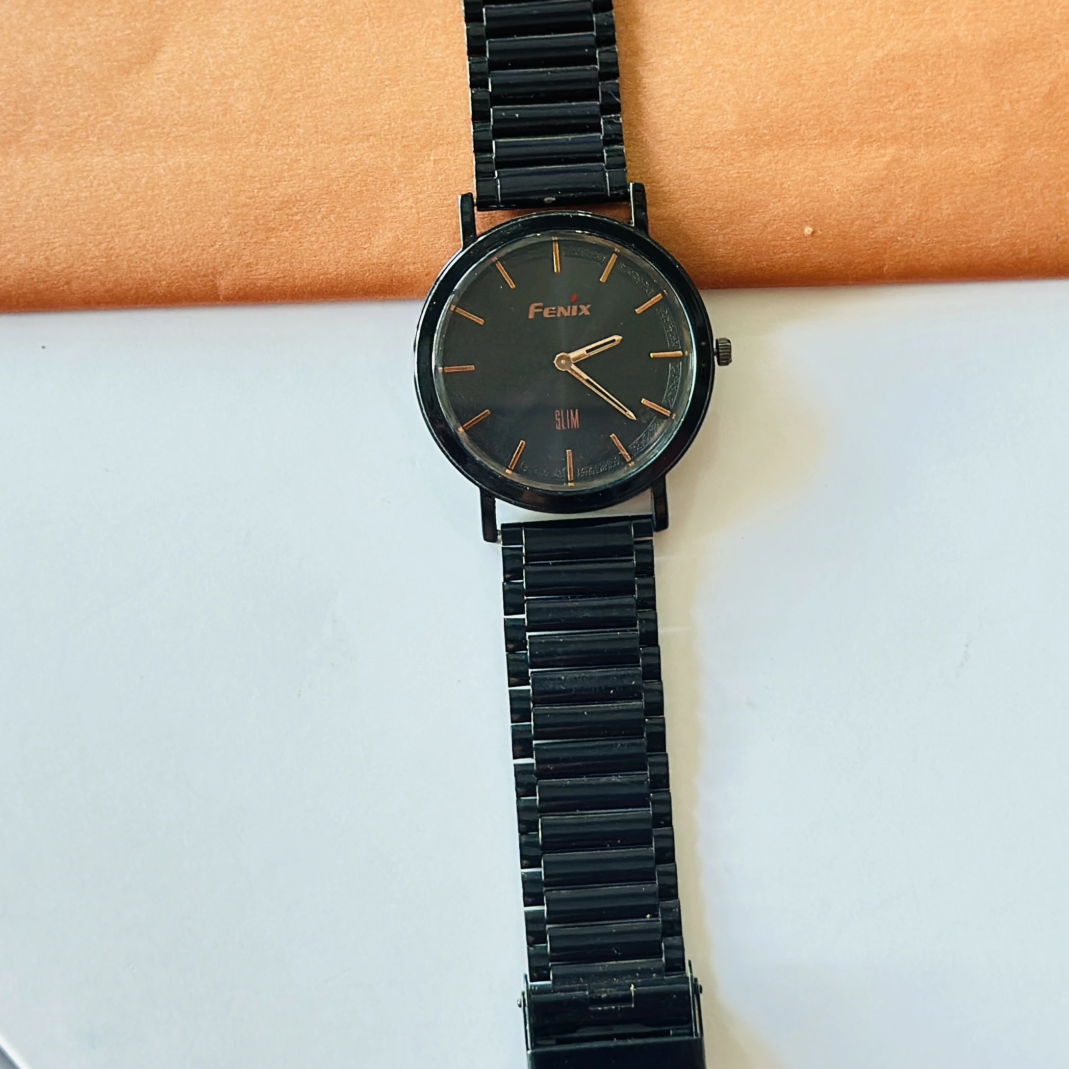Fenix Slim black analog wristwatch with a matching metal band.